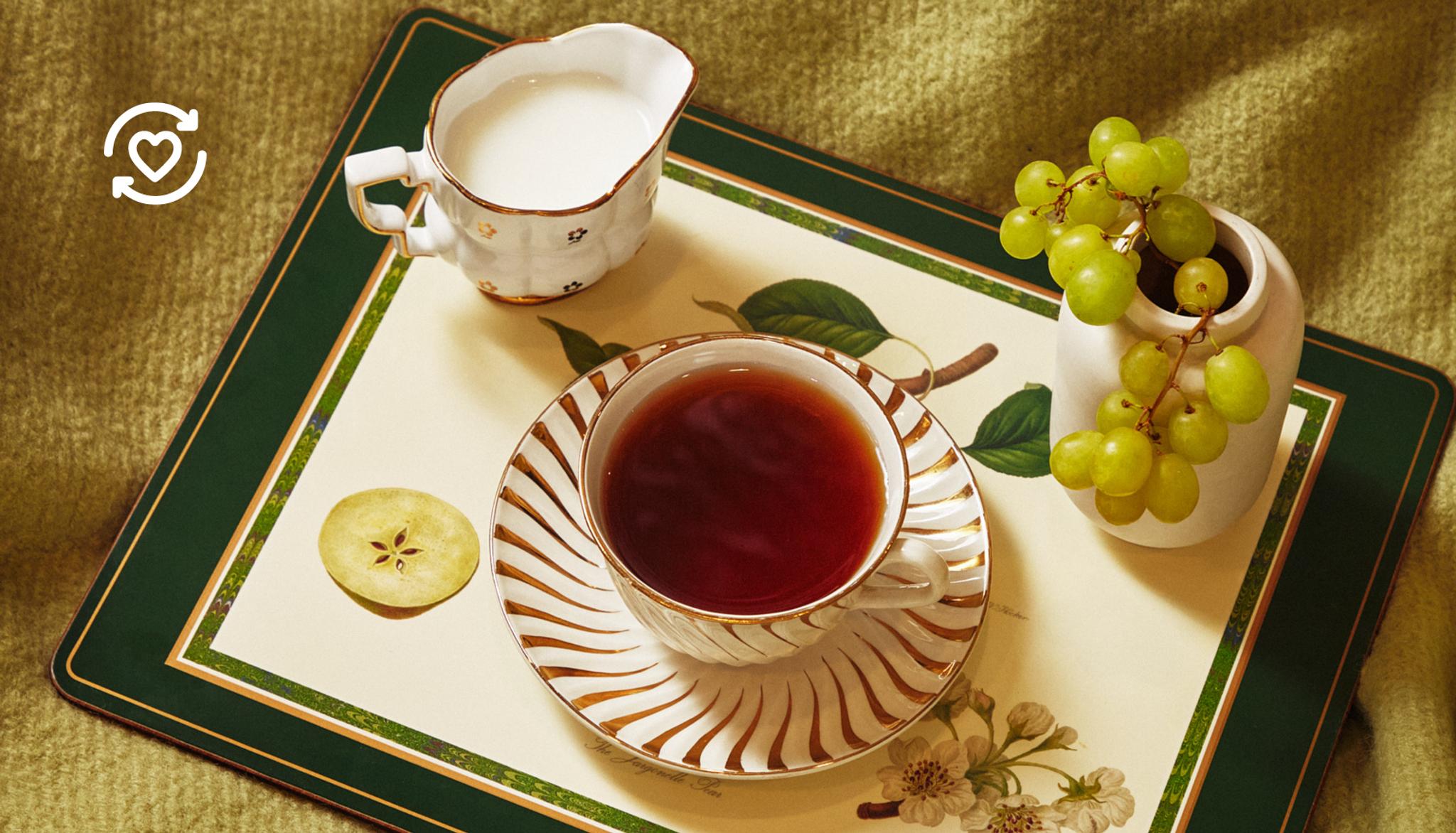 En tekopp och en liten mjölkkanna på en blommig bricka