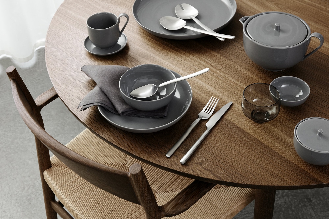 Spisebestikk dekket på et trebord med skåler og tallerkener