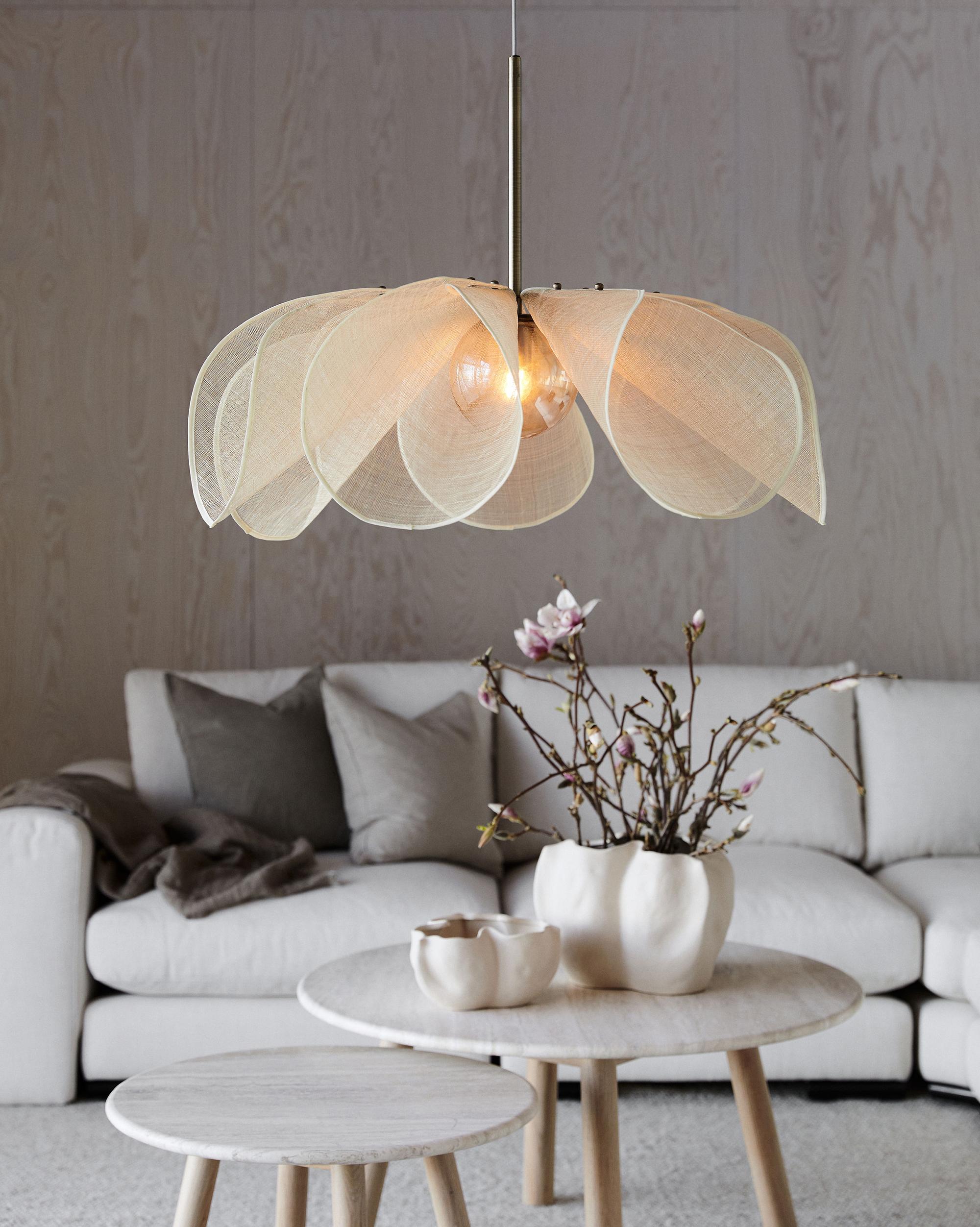 Markslöjd taklampa formad som en blomma hängandes ovanför ett vitt soffbord
