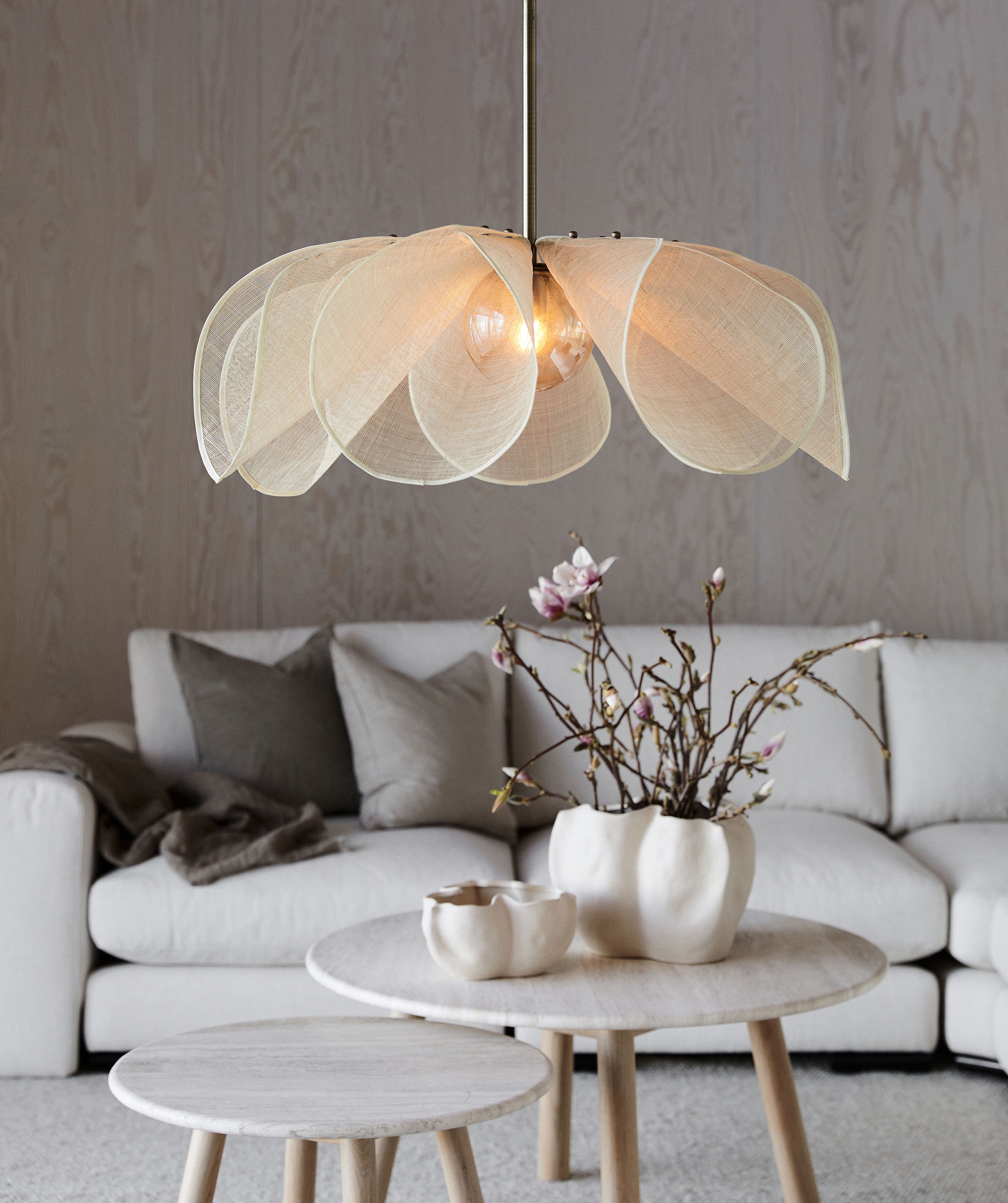 Markslöjd taklampa formad som en blomma hängandes ovanför ett vitt soffbord