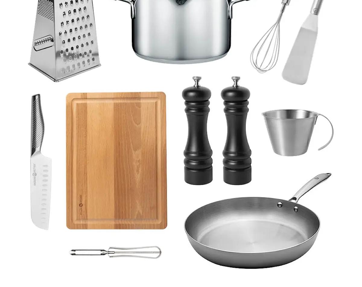 Uppsättning köksredskap med kastrull, stekpanna, rivjärn, skärbräda, kniv, visp, stekspade, skalare, måttkanna och salt- och pepparkvarnar på vit bakgrund.