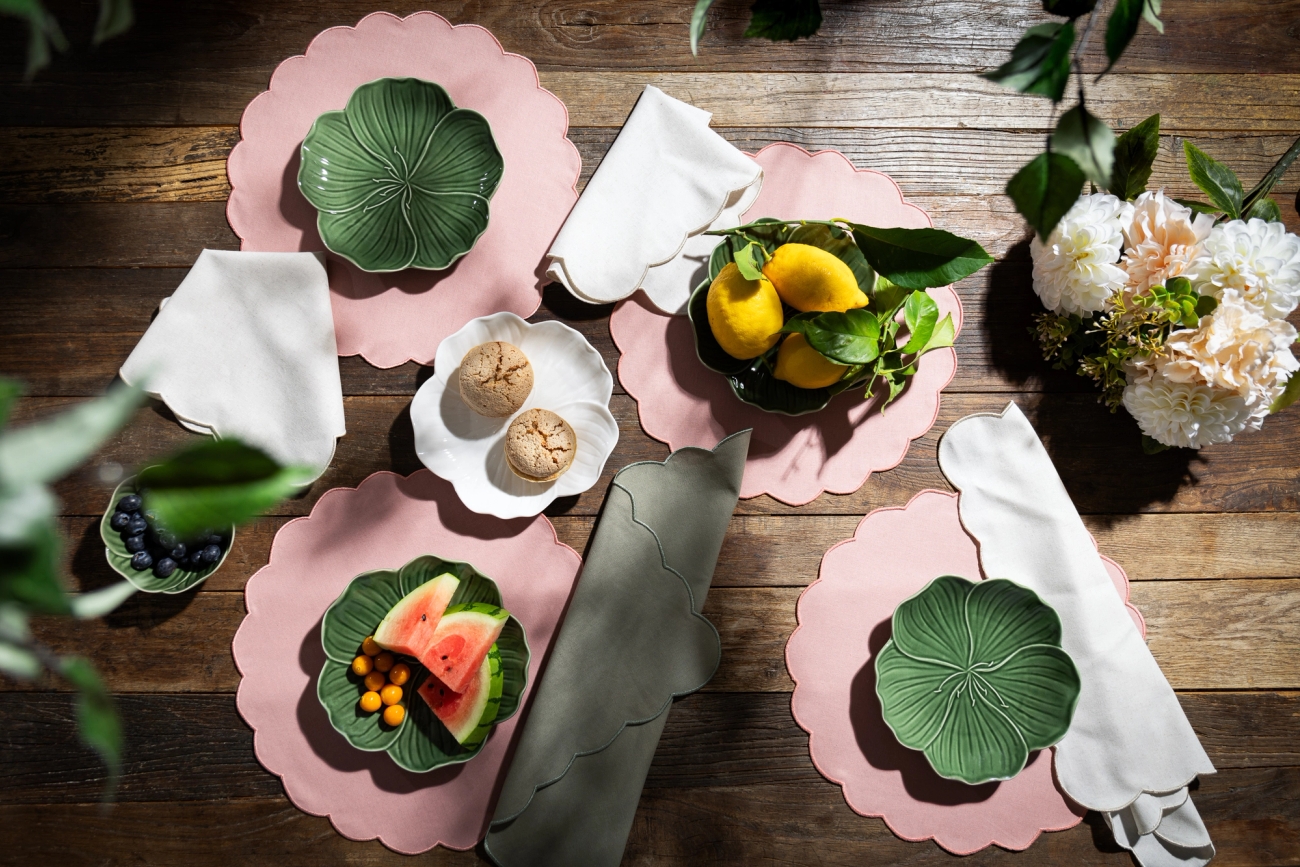 Rosa bordstabletter med gröna tallrikar som är uppdukade på ett träbord