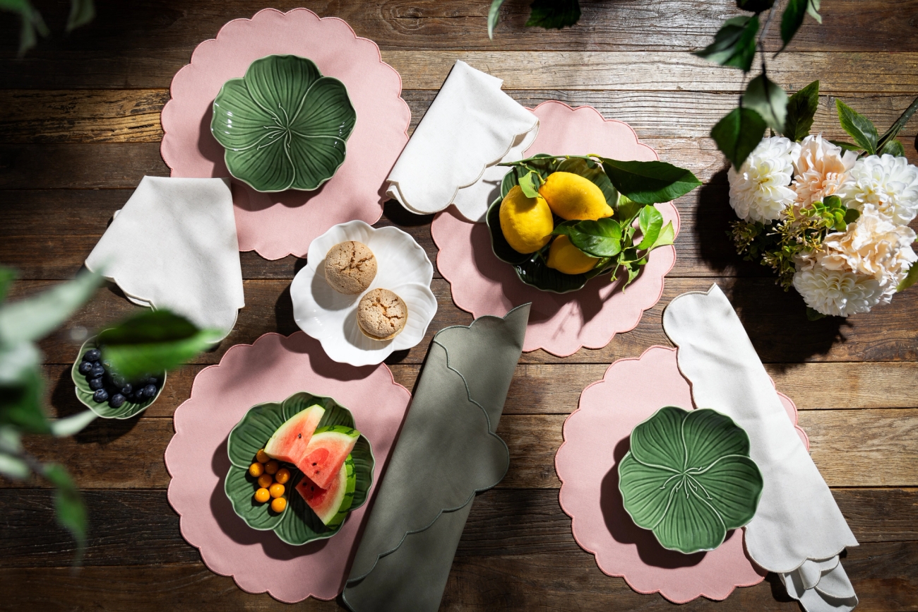 Rosa bordstabletter med gröna tallrikar som är uppdukade på ett träbord
