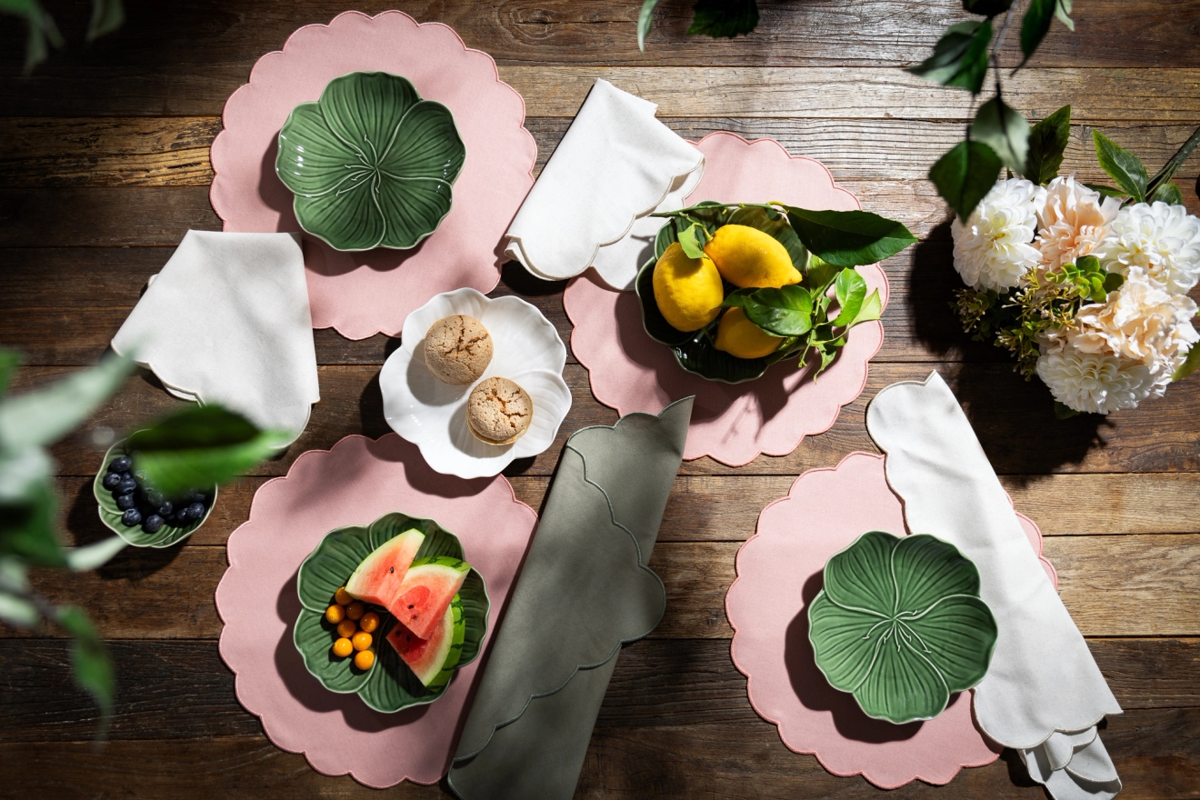 Rosa bordstabletter med gröna tallrikar som är uppdukade på ett träbord