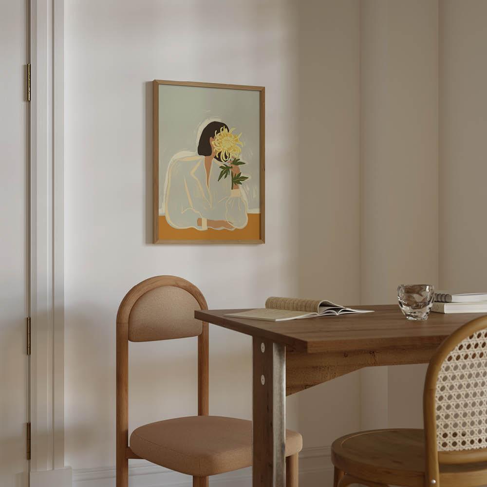 Ljust matrum med träbord, stoppade stolar och en tavla av en person som håller en blomma framför ansiktet.