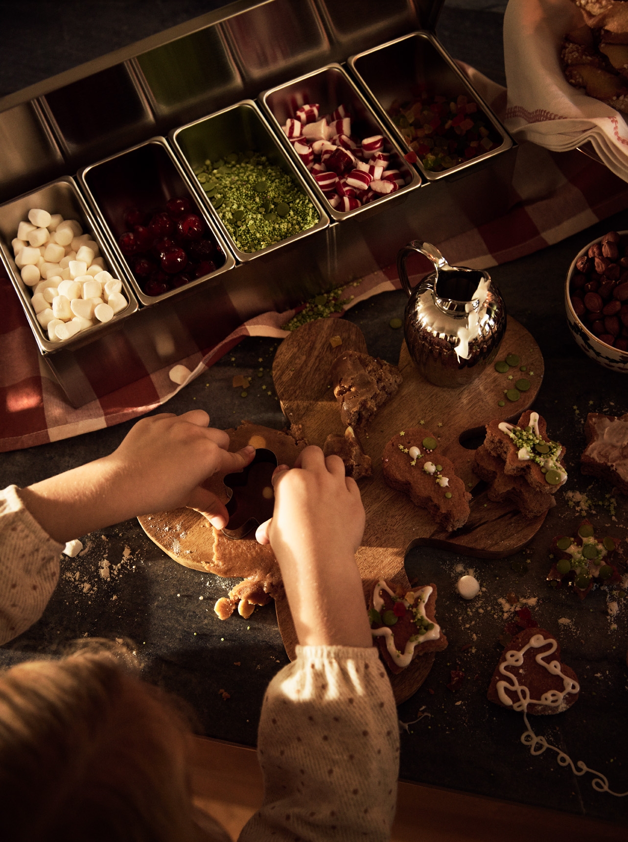 Barn bakar och dekorerar pepparkakor med färgglatt julgodis.