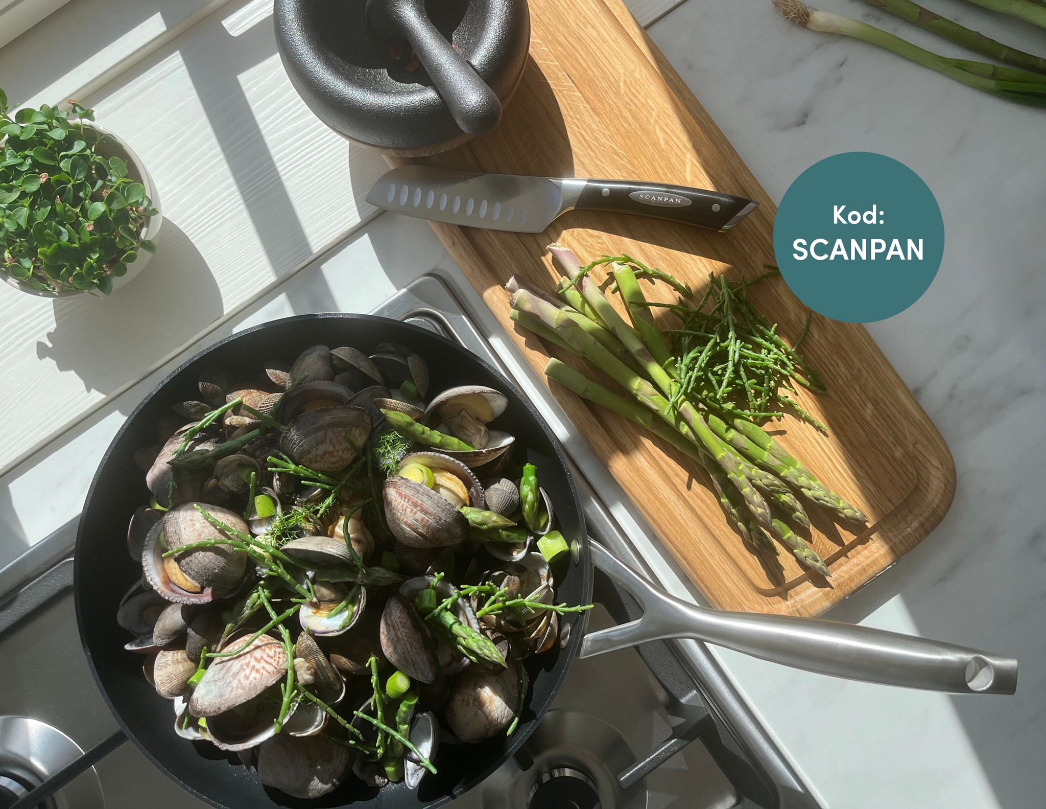 A pan of clams, asparagus, and samphire cooking on a stove, with raw ingredients and a knife on a cutting board. A graphic states 'Kod: SCANPAN'.