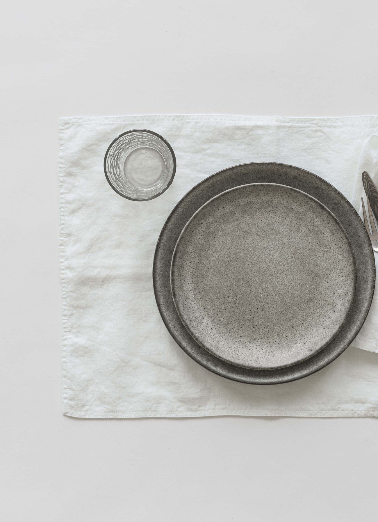 Hvit bordbrikke i lin på hvitt bord med servise på