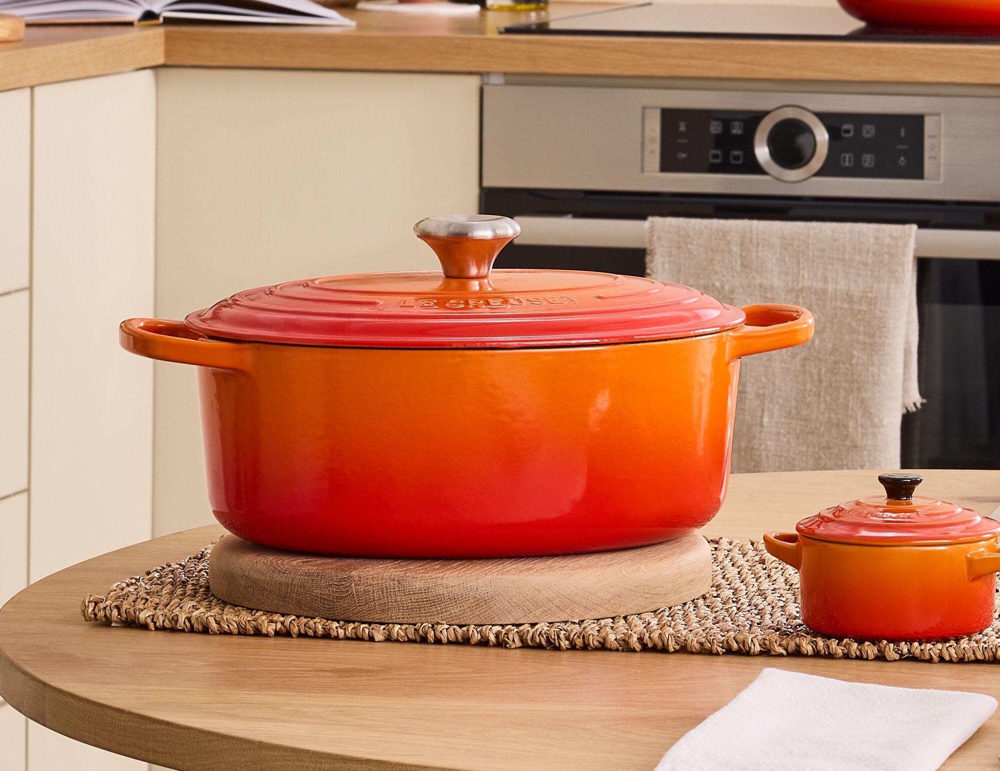 Keittiö, jossa on oranssien keitto- ja ruokailuvälineiden pöytä, mukaan lukien suuri pata ja siihen sopivat lautaset.