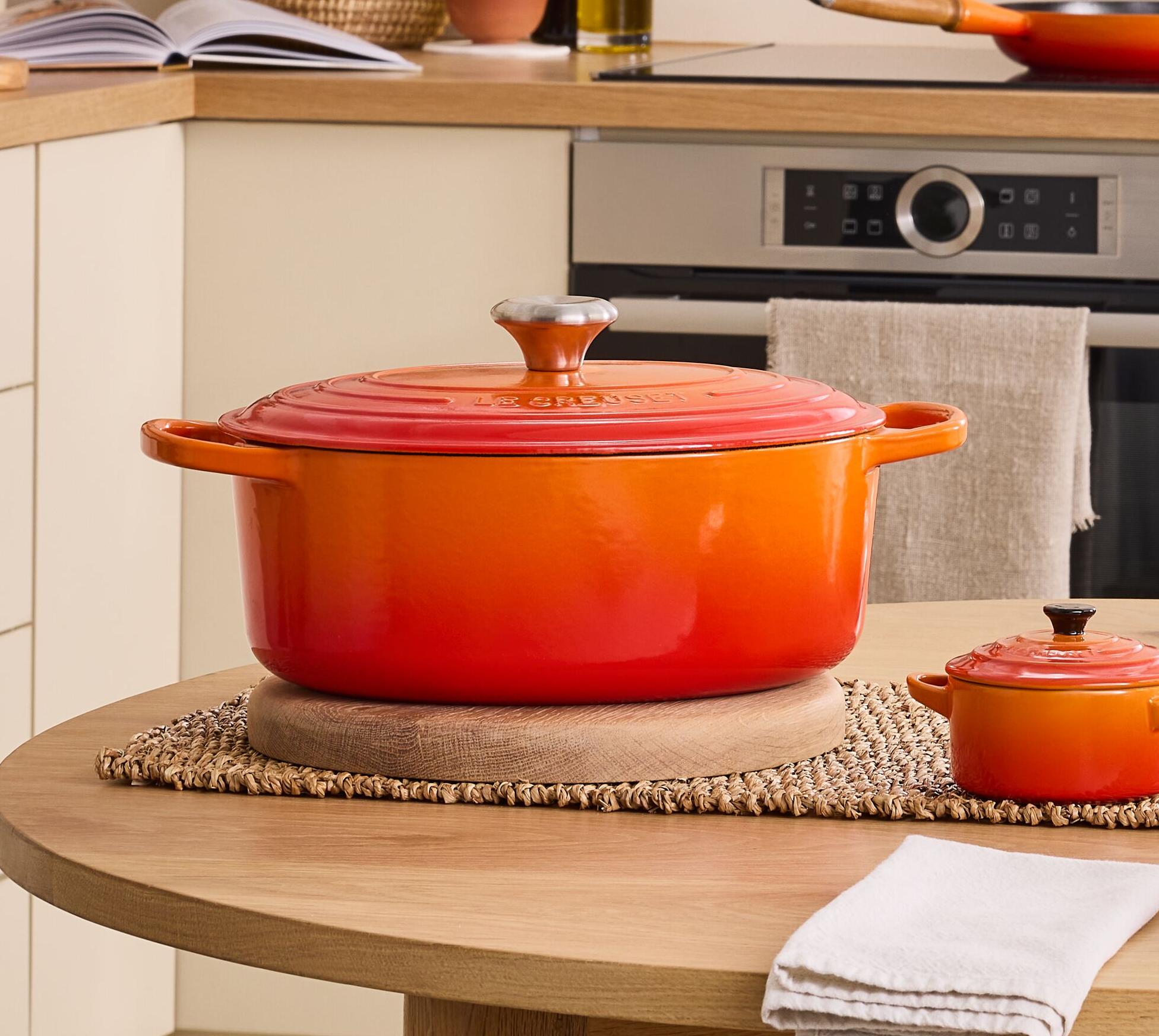 Keittiö, jossa on oranssien keitto- ja ruokailuvälineiden pöytä, mukaan lukien suuri pata ja siihen sopivat lautaset.