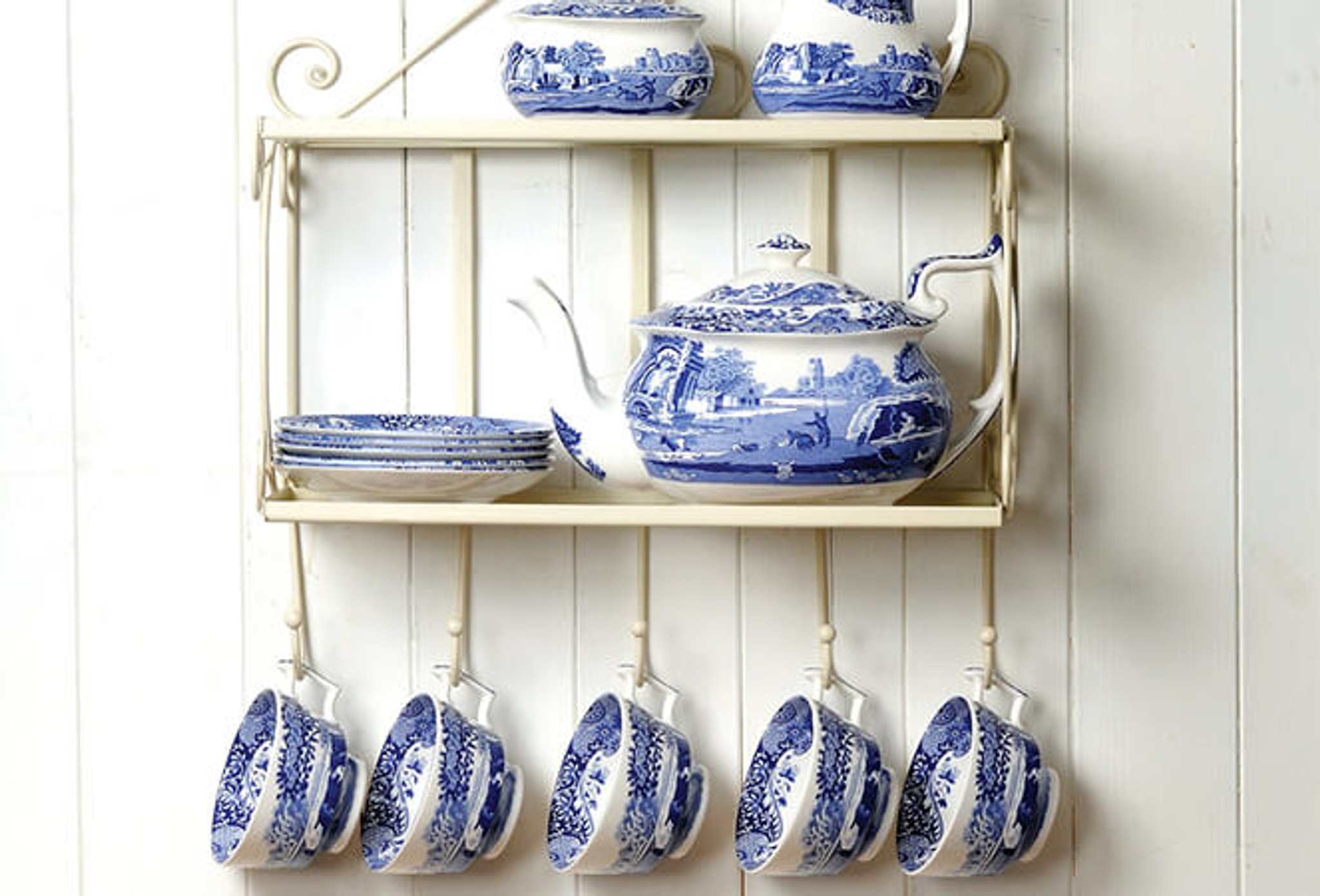 a shelf with blue and white dishes and cups hanging from it .