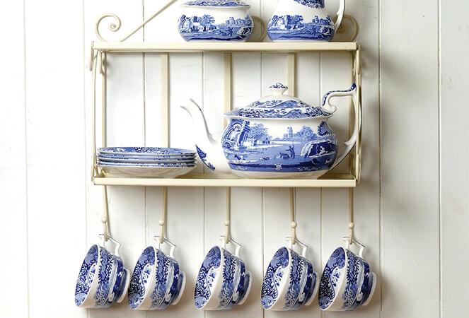 a shelf with blue and white dishes and cups hanging from it .