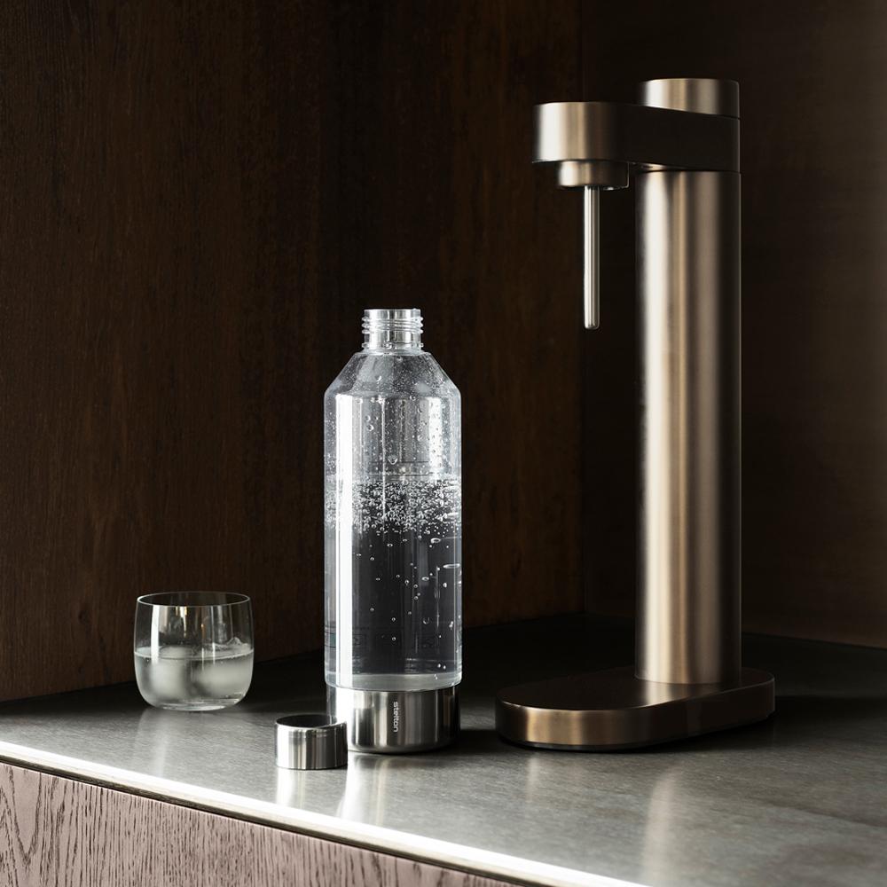 Kolsyremaskin i brun metallic mot en mörk vägg från Stelton Brus