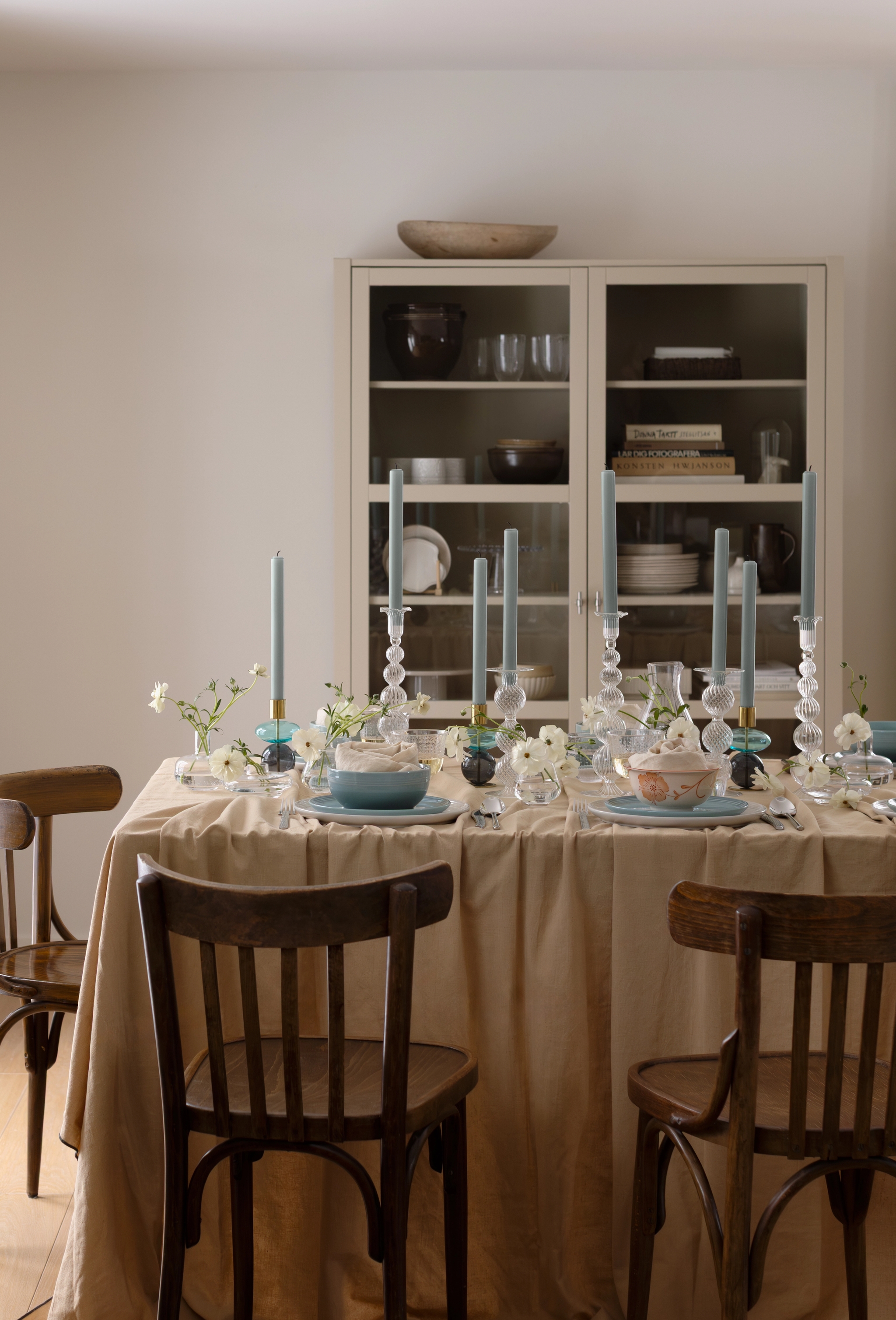 Et spisebord dekket med blå lys og hvite blomster, med en kjøkkenbenk på venstre side