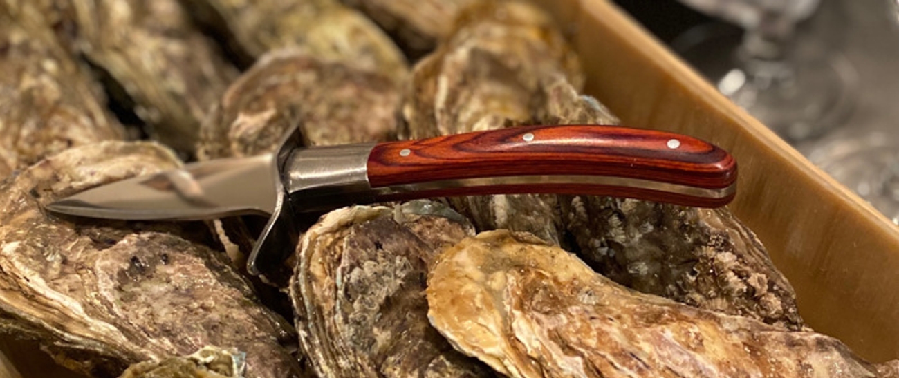 Ostronknivar med träskaft liggandes på ostron