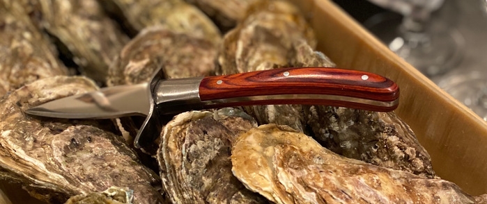 Ostronknivar med träskaft liggandes på ostron
