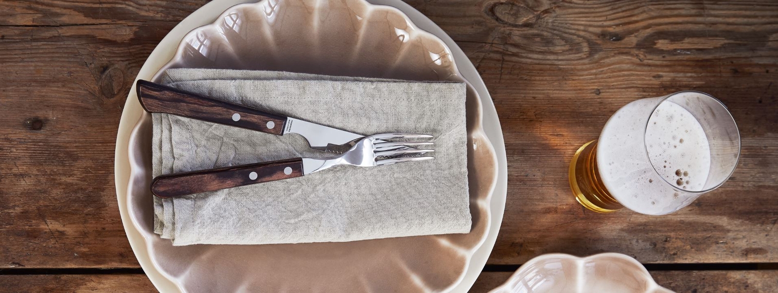 Grillbestick på beige lotus tallrik samt en öl bredvid