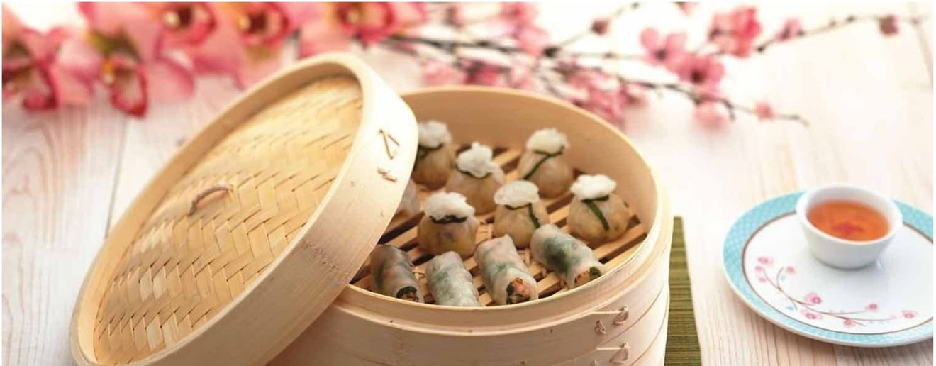 Ångkokare i bambu med ångkokta dumplings och rosa blommor