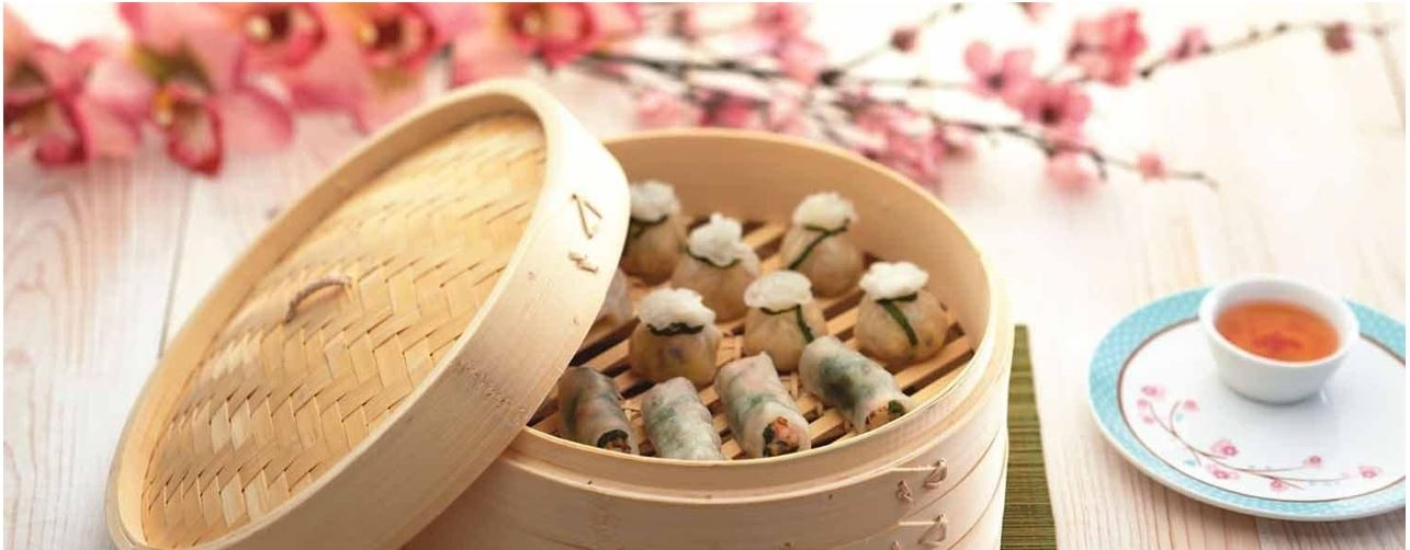 Ångkokare i bambu med ångkokta dumplings och rosa blommor