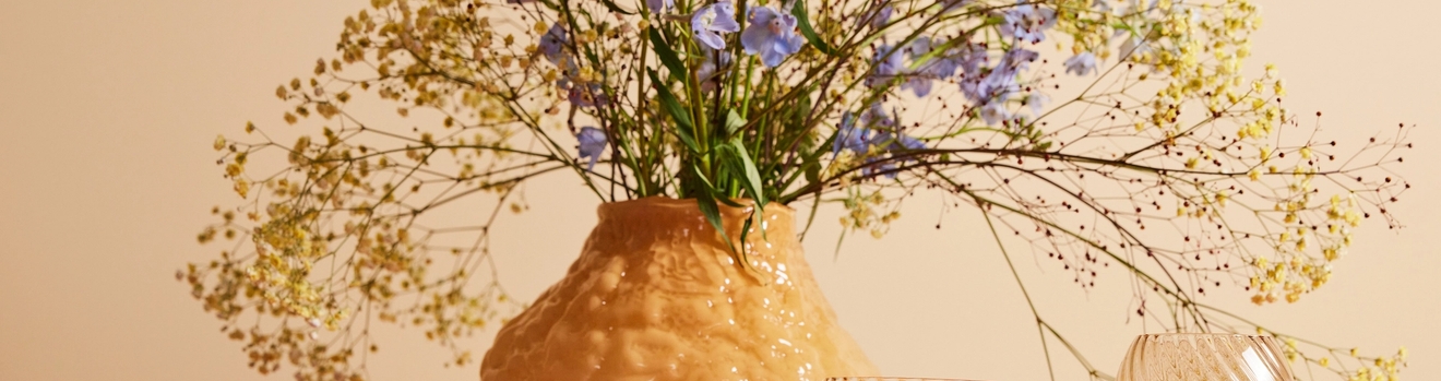 keltainen iso maljakko jossa keltaiset ja violetit kukat keltaisessa huoneessa