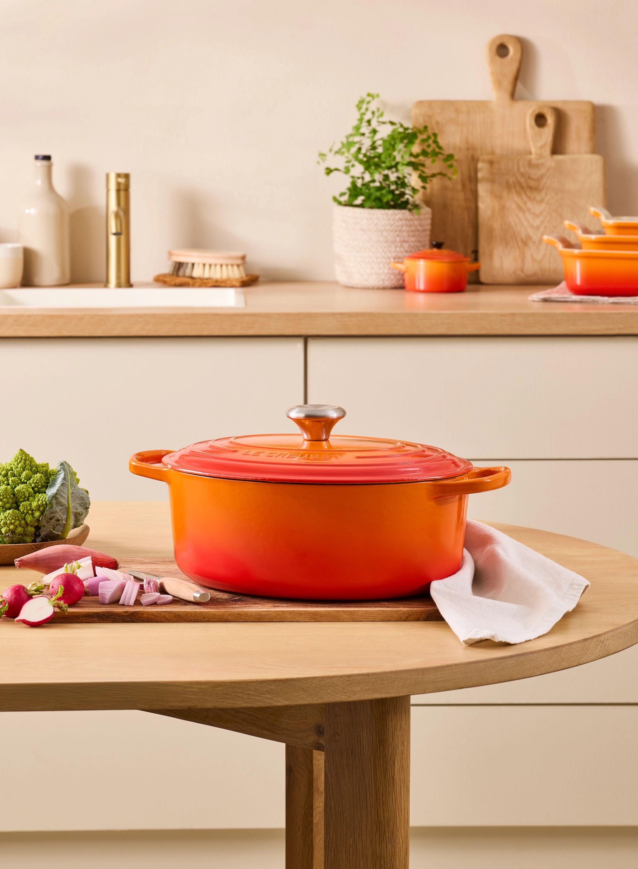 Oransje støpejernsgryte som står på et trebord