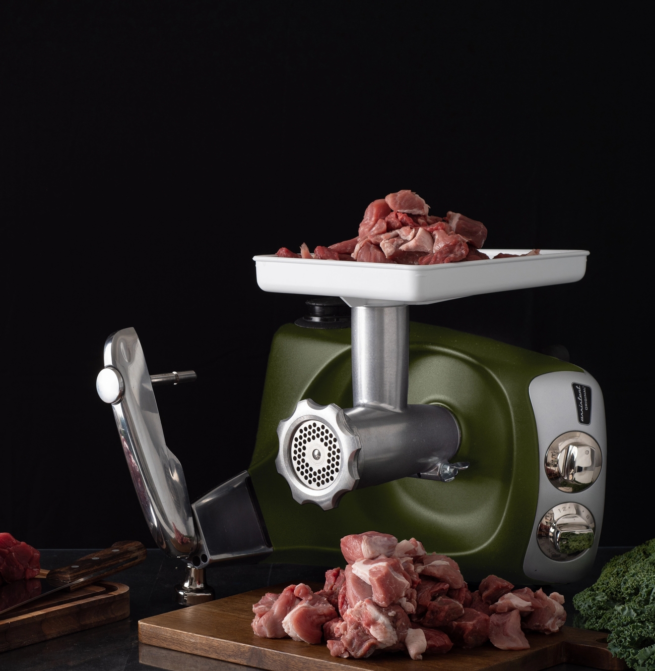 Lihamylly ja raa'at lihapalat puisella leikkuulaudalla