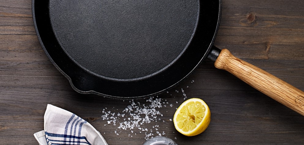 Valurautapannu puukahvalla puisella työtasolla