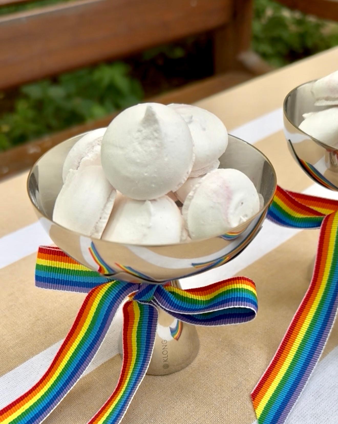 a bowl of marshmallows with a rainbow ribbon on a table .