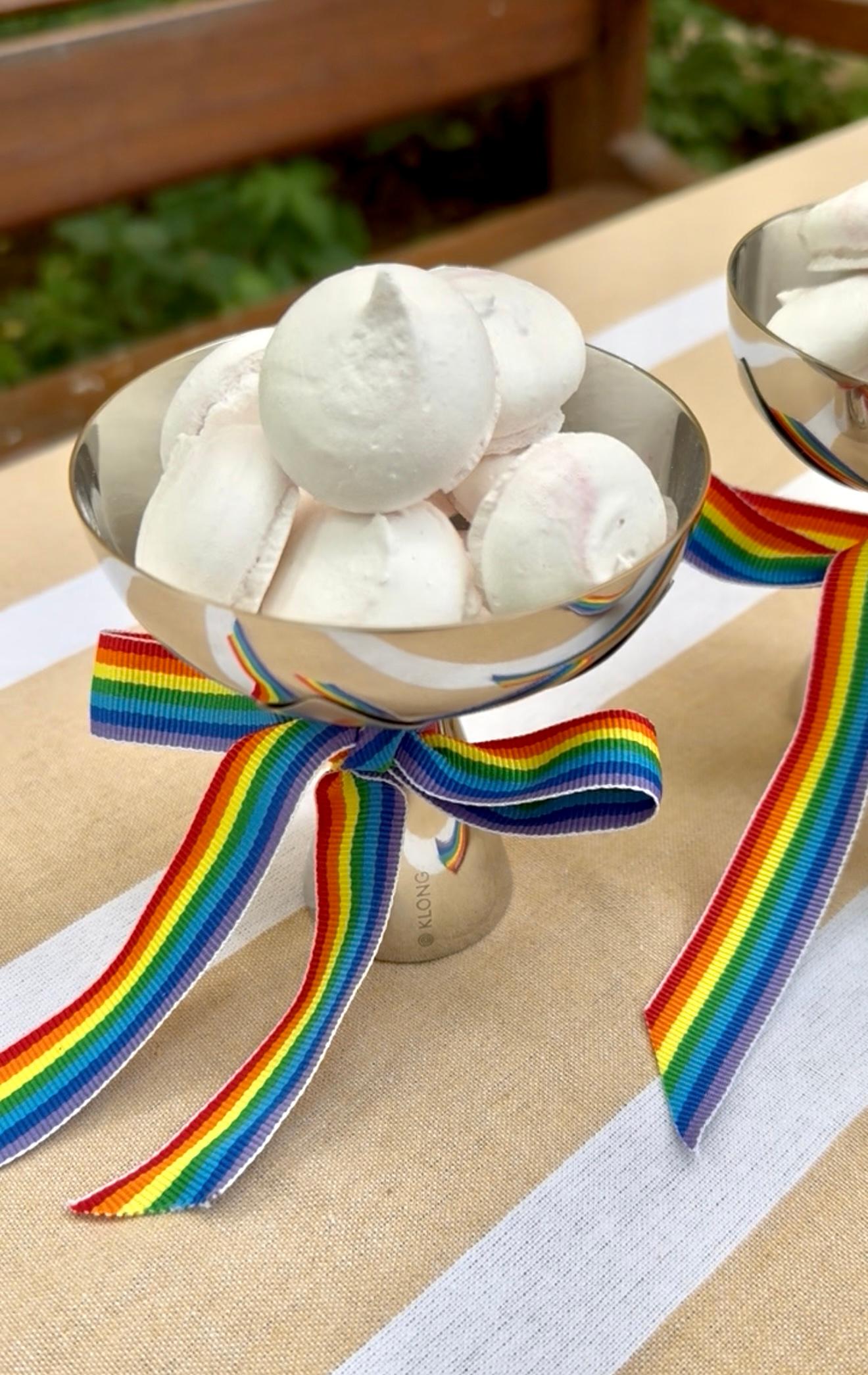 a bowl of marshmallows with a rainbow ribbon on a table .