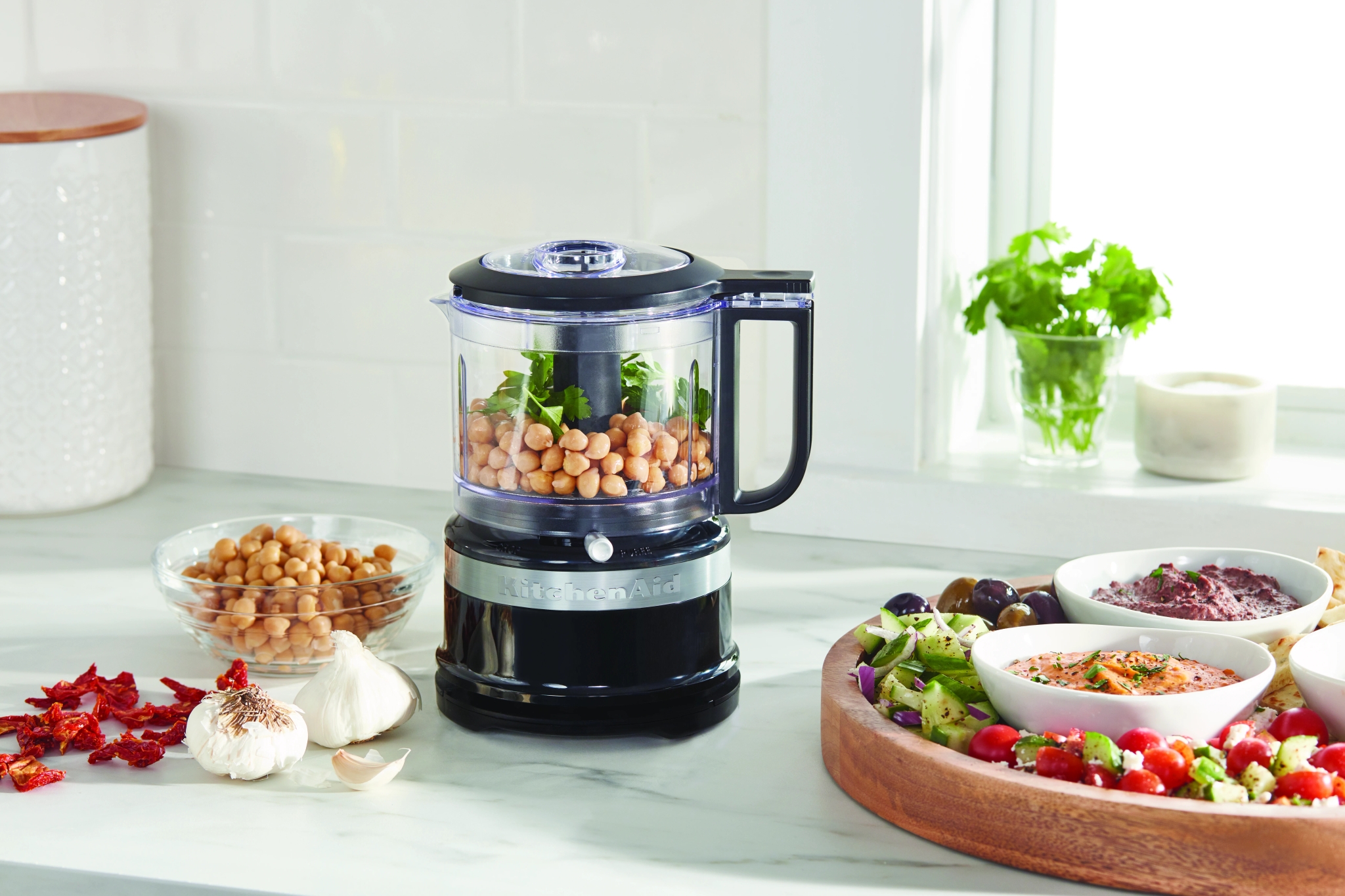 Kitchenaid monitoimikone keittiön työtasolla jossa kikherneitä ja yrttejä
