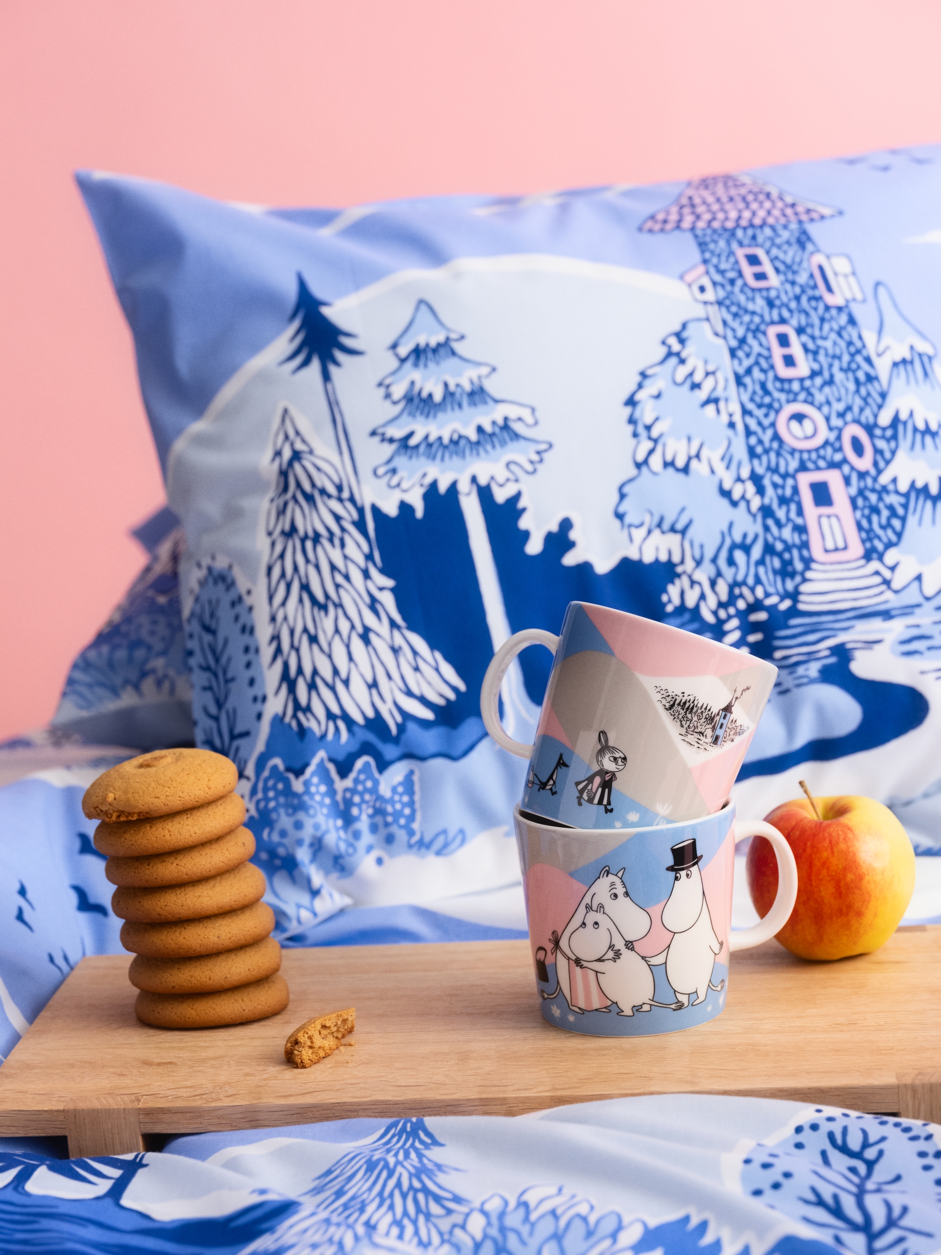 Ny Mummikolleksjon i rosa og blå pastellfarger. Et frokostbrett med koppen fra kolleksjonen står på en seng med sengetøy fra kolleksjonen.