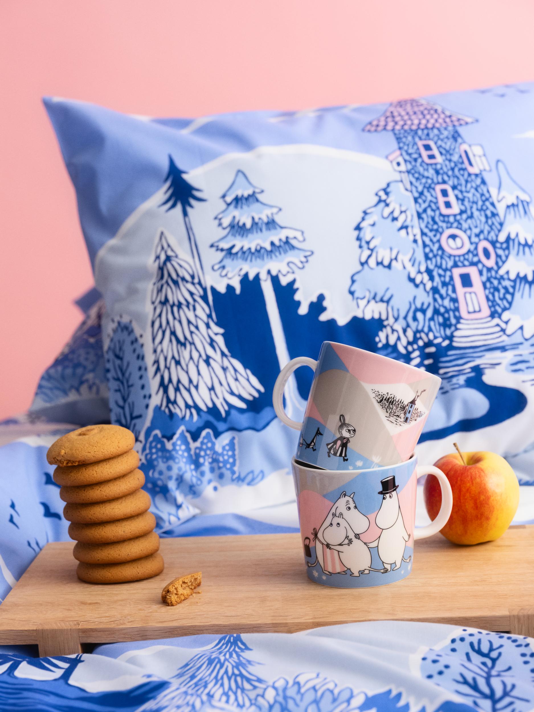 Ny Mummikolleksjon i rosa og blå pastellfarger. Et frokostbrett med koppen fra kolleksjonen står på en seng med sengetøy fra kolleksjonen.