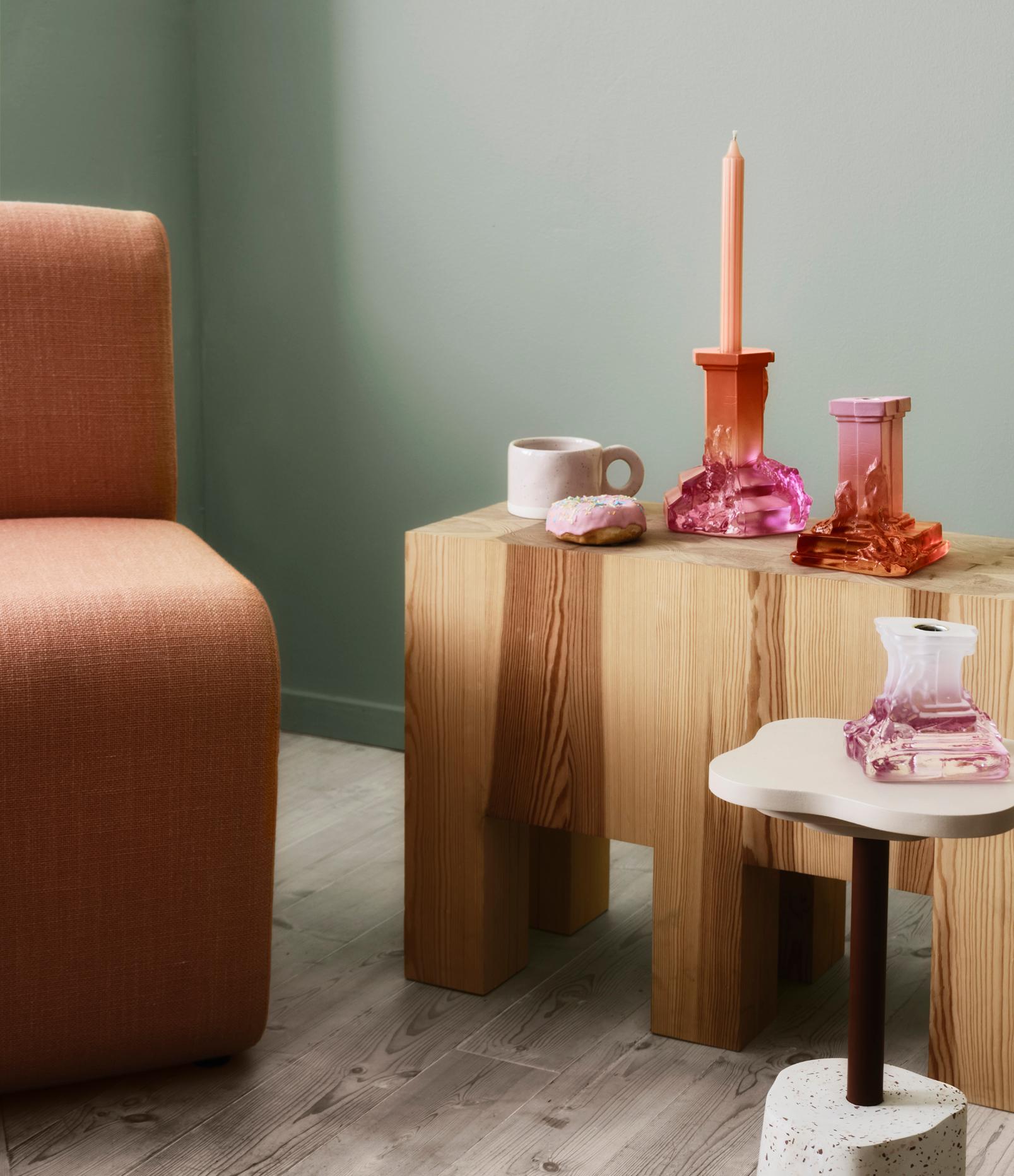 En organge fotölj med ett träbord brevis sig, på är det två färglada ljusstakar och en kaffemugg