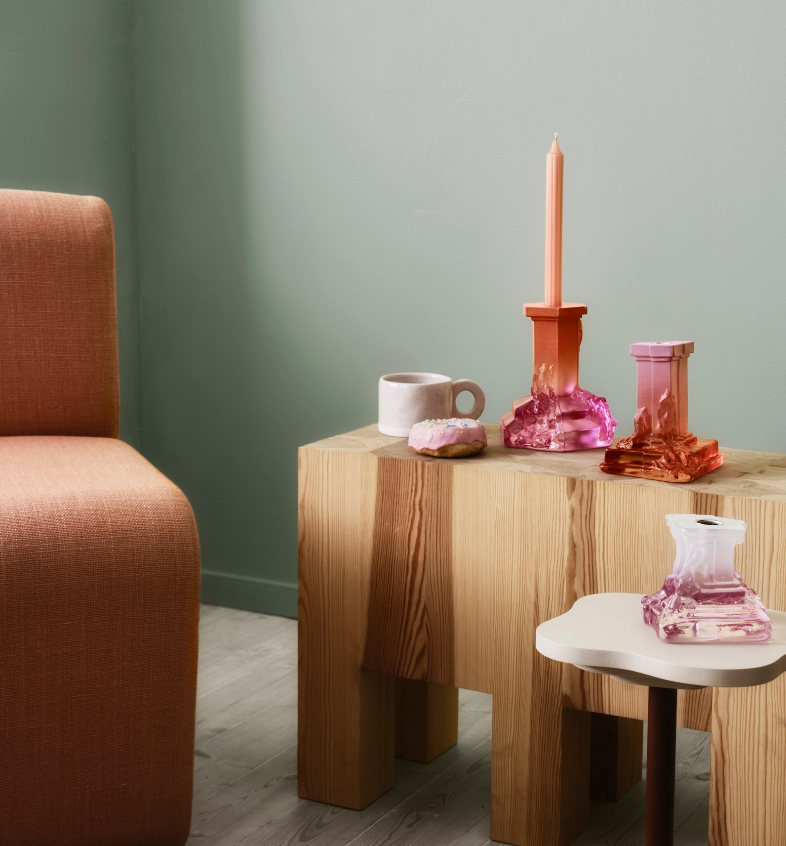 En organge fotölj med ett träbord brevis sig, på är det två färglada ljusstakar och en kaffemugg