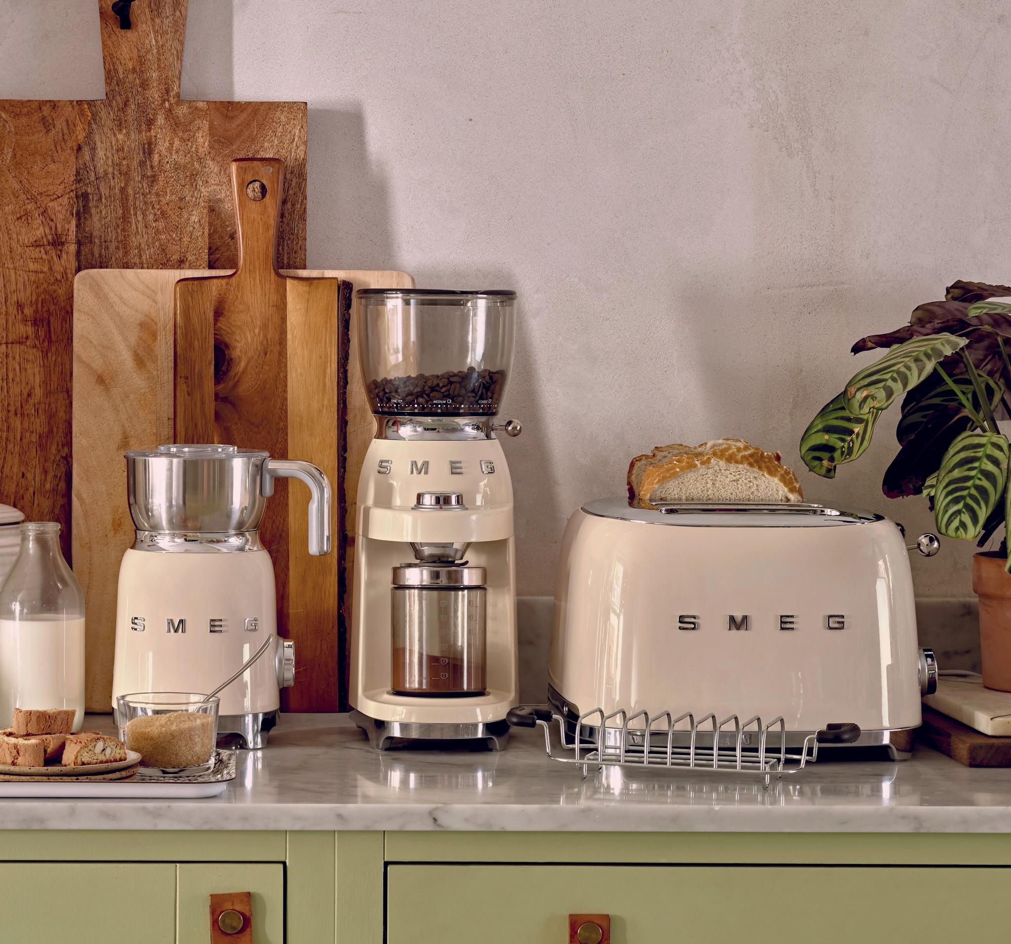 Stilfullt kjøkkenbenk med kremfargede SMEG-kjøkkenapparater, brød og kaffe i et lyst, moderne interiør.