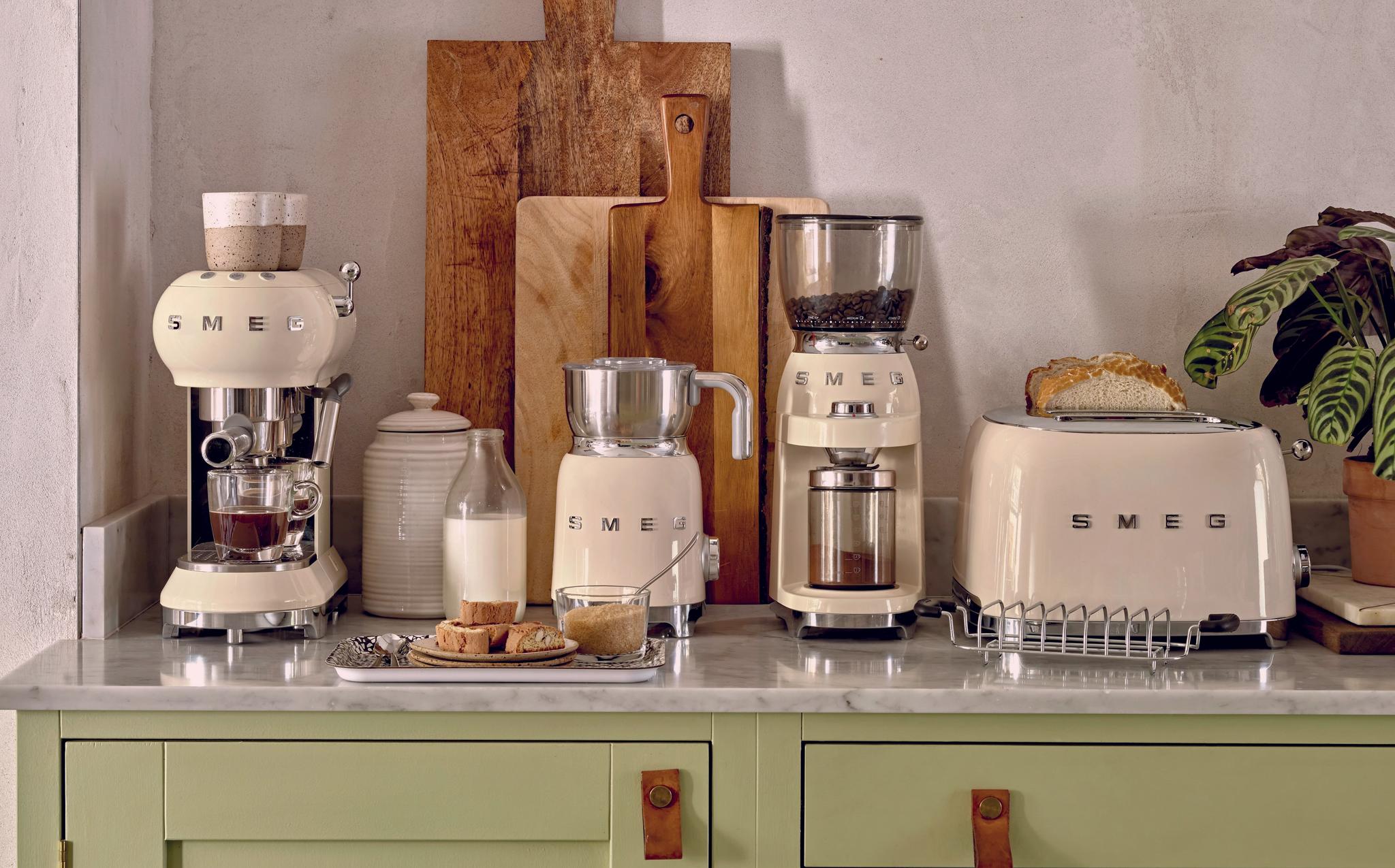 Stilfullt kjøkkenbenk med kremfargede SMEG-kjøkkenapparater, brød og kaffe i et lyst, moderne interiør.
