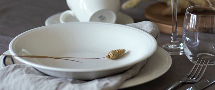 Dype tallerkener hvite dekket på med beige linserviett og med et strå