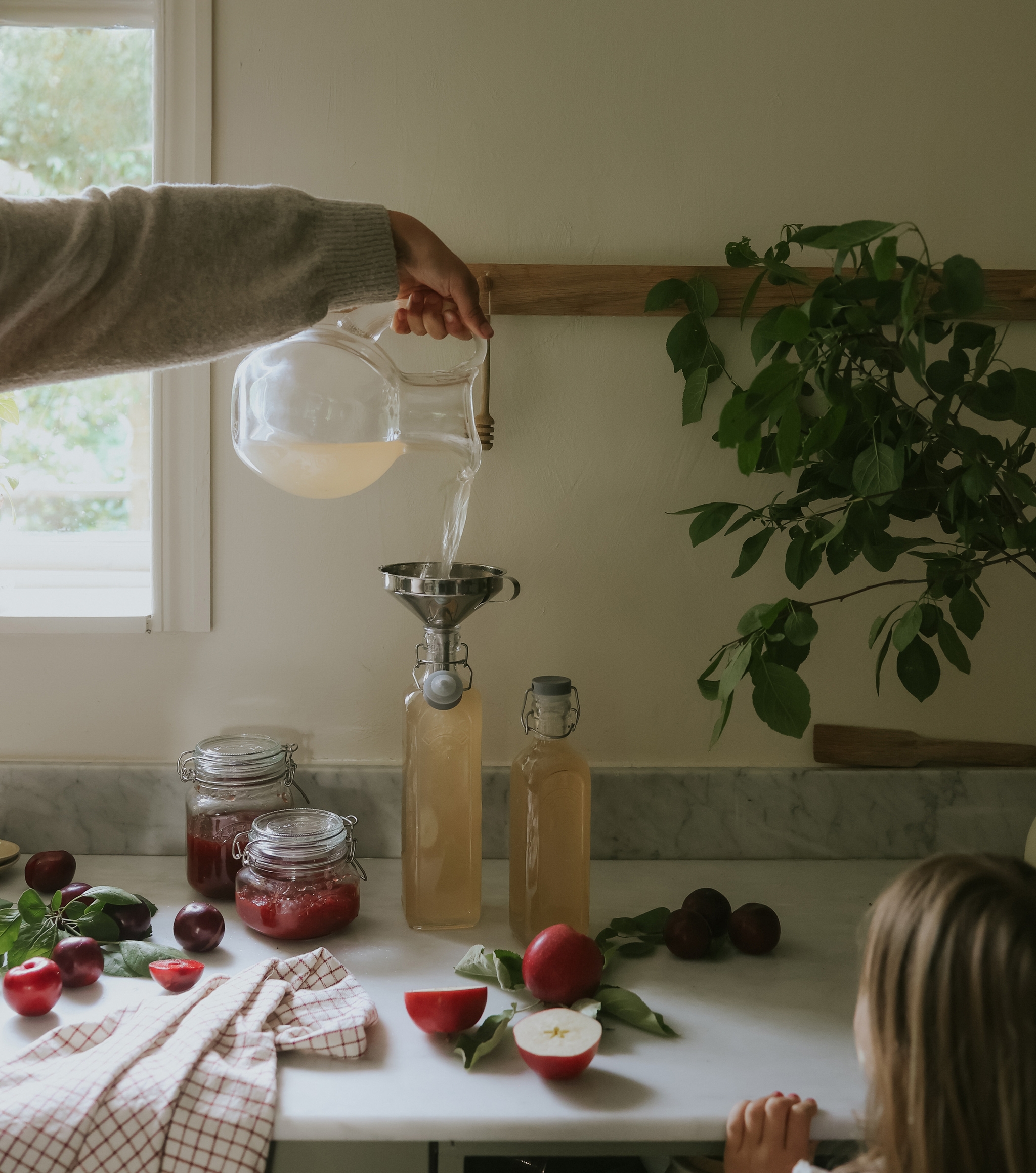 Valmista oma hillo ja mehu - lasipurkit ja lasipullot eri hedelmien kera keittiön työtasolla