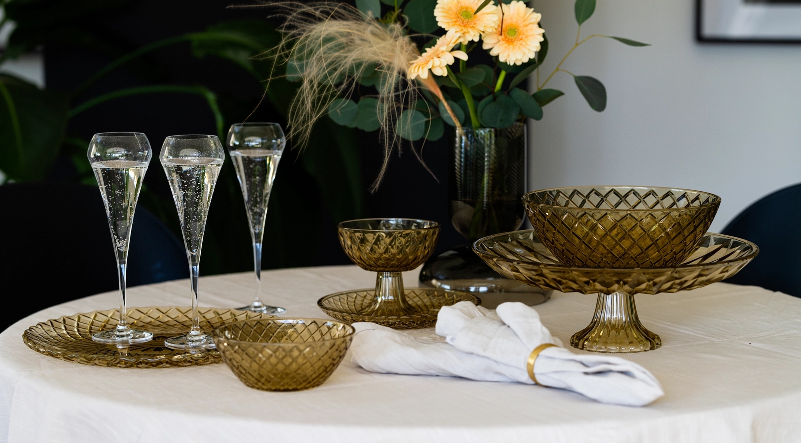 Ett dukat bord med champagneglas, glasskålar och en vas med gula blommor