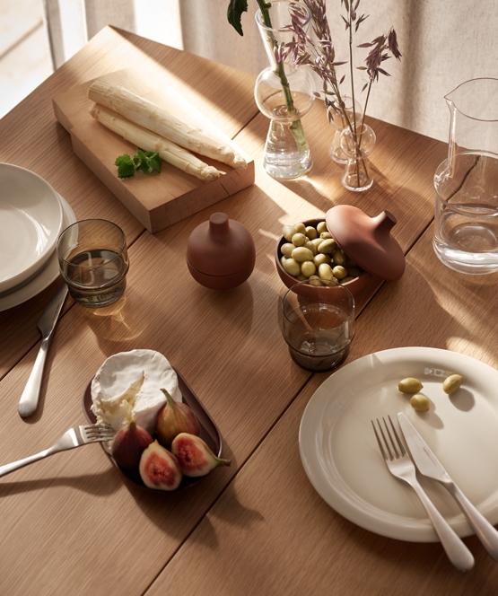 pöytä lautasilla ja aterimilla sekä kukkamaljakko