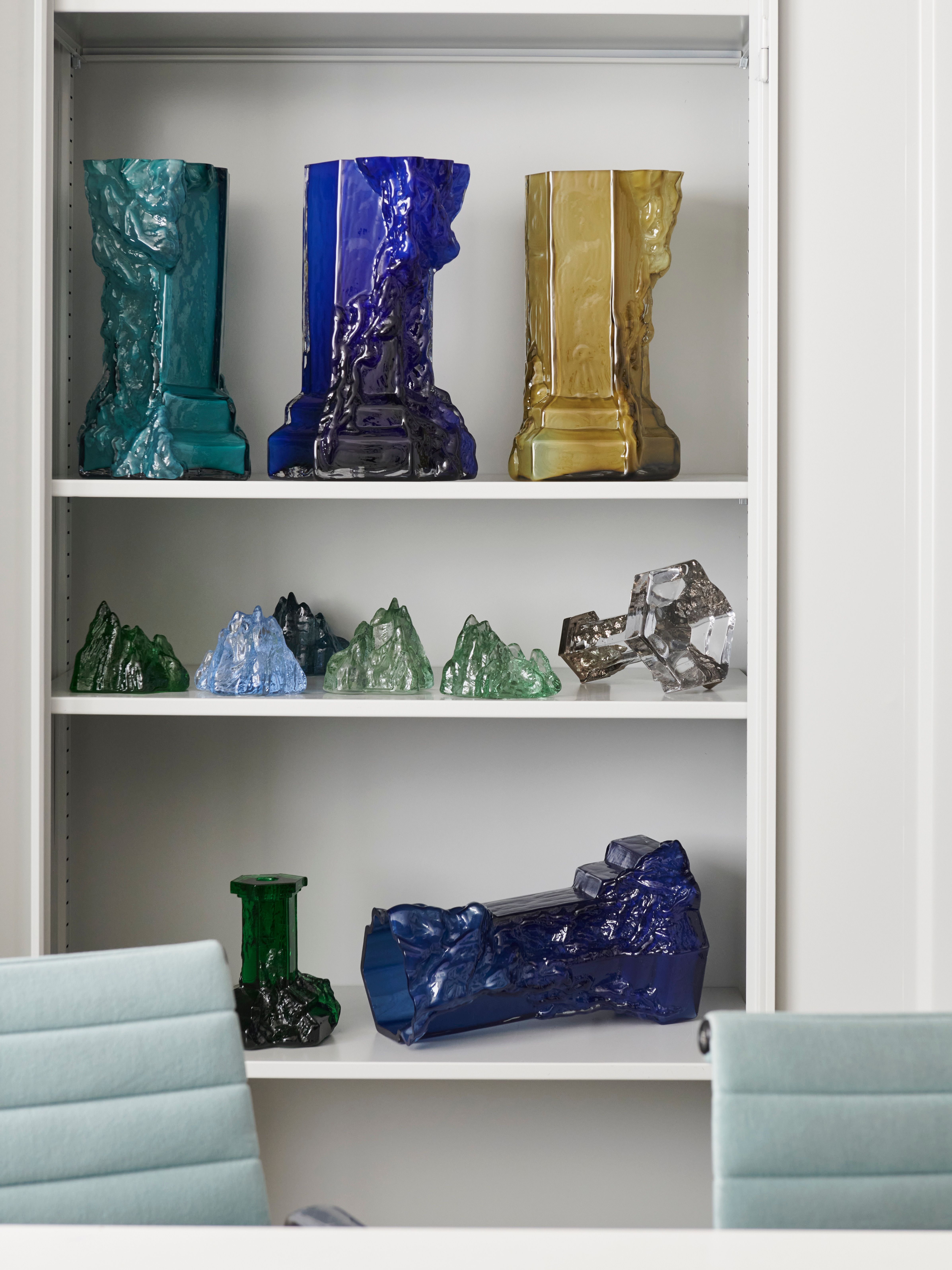 En vit hylla med ljusstakar i olika färger formade som berg