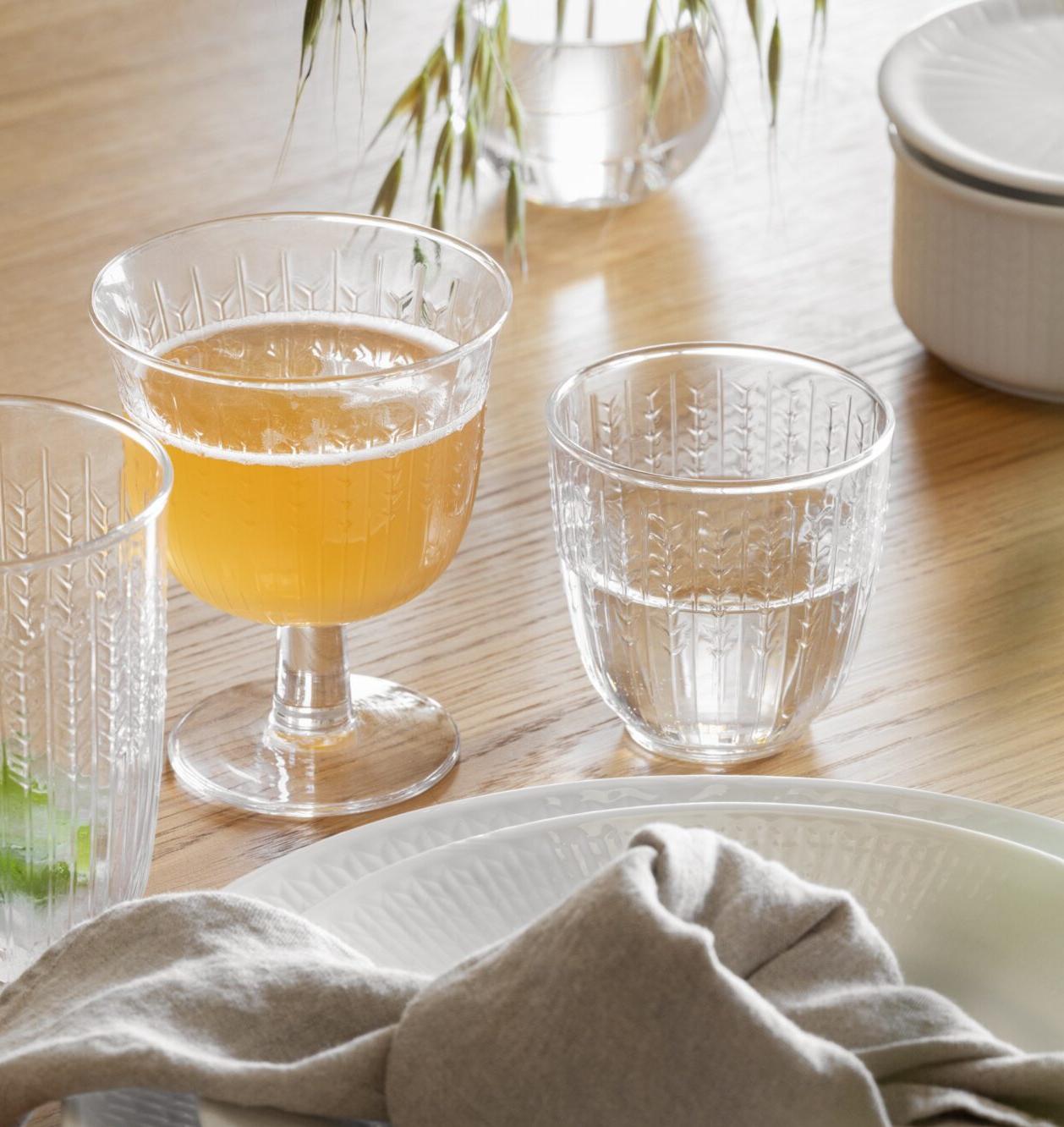 Elegant dukning på ett träbord med vitt porslin, linneservett, mönstrade glas och karaff.
