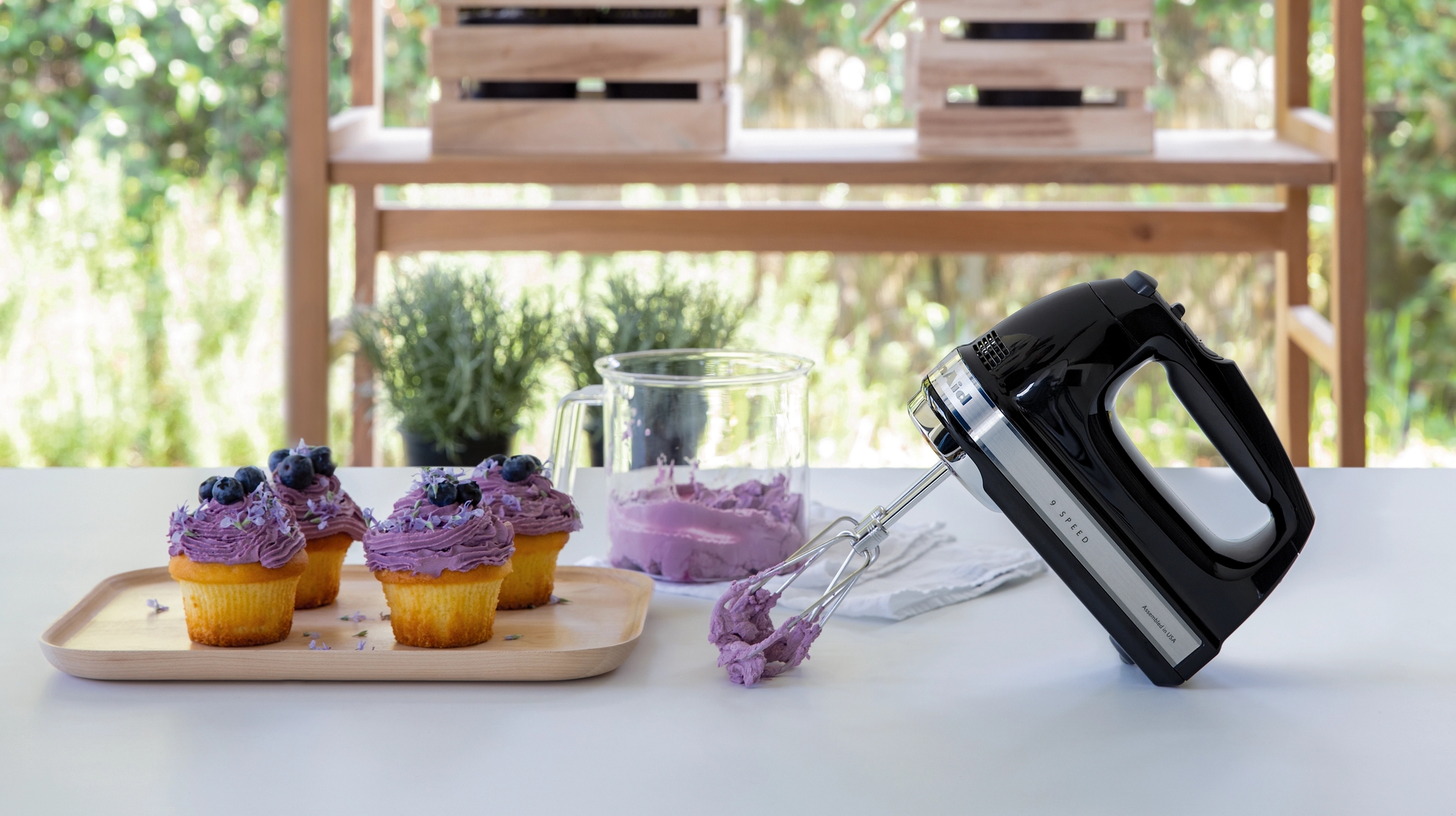 KitchenAid håndmikser på kjøkkenbenk med vispet blåbærkrem på muffins