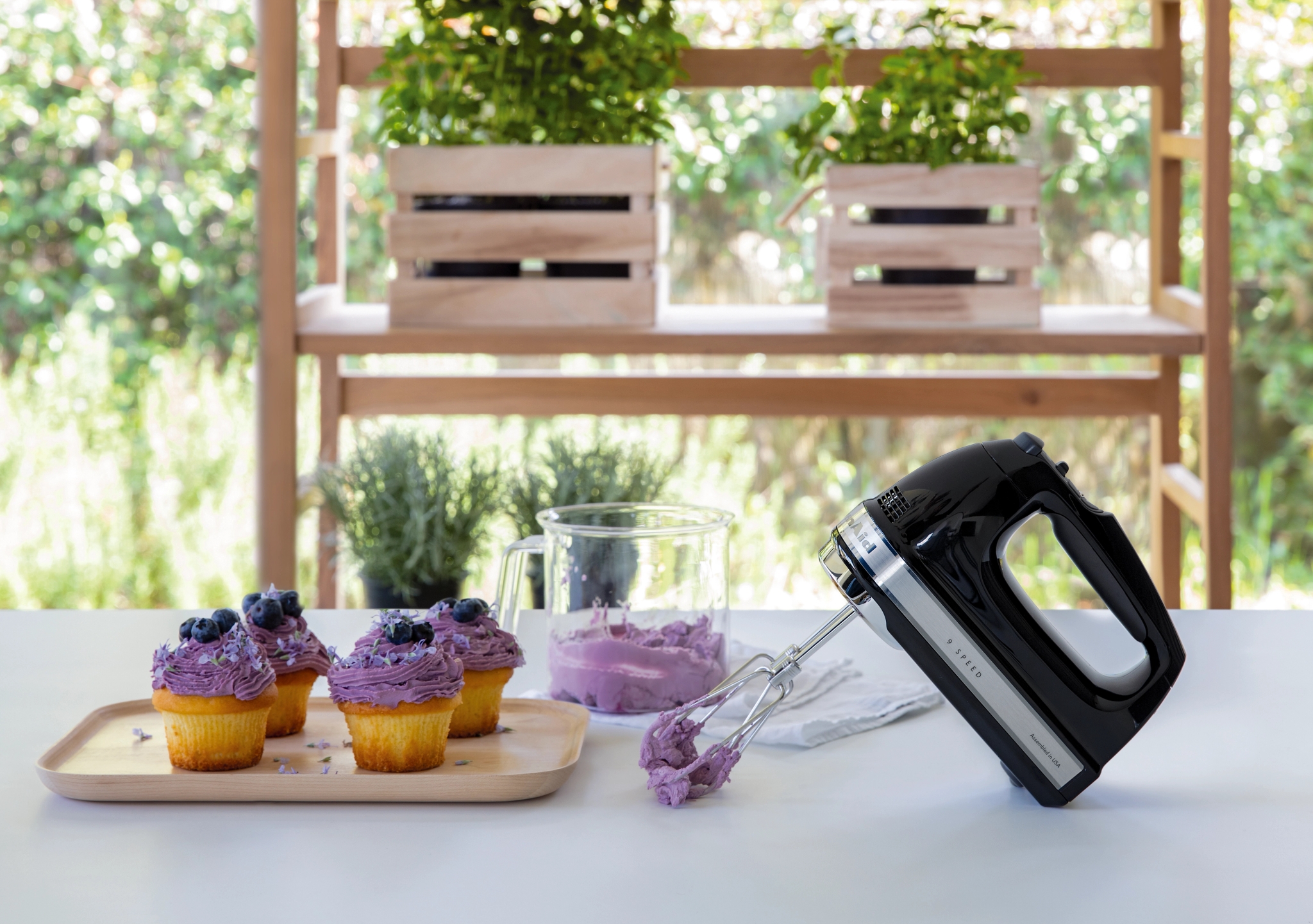 KitchenAid håndmikser på kjøkkenbenk med vispet blåbærkrem på muffins