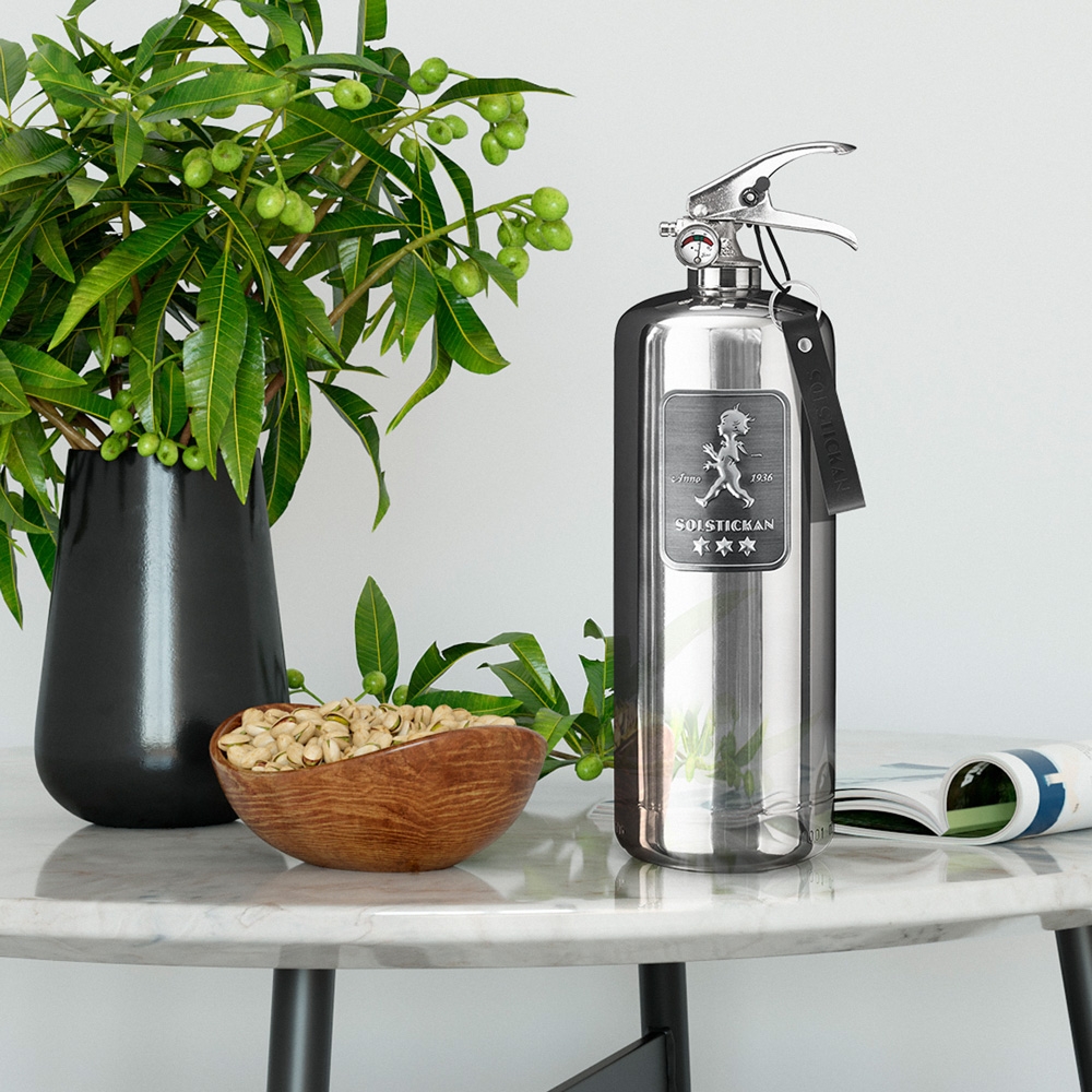 Solstickan Brandsläckare 2 kg Steel Edition på ett bord med vit bakgrund