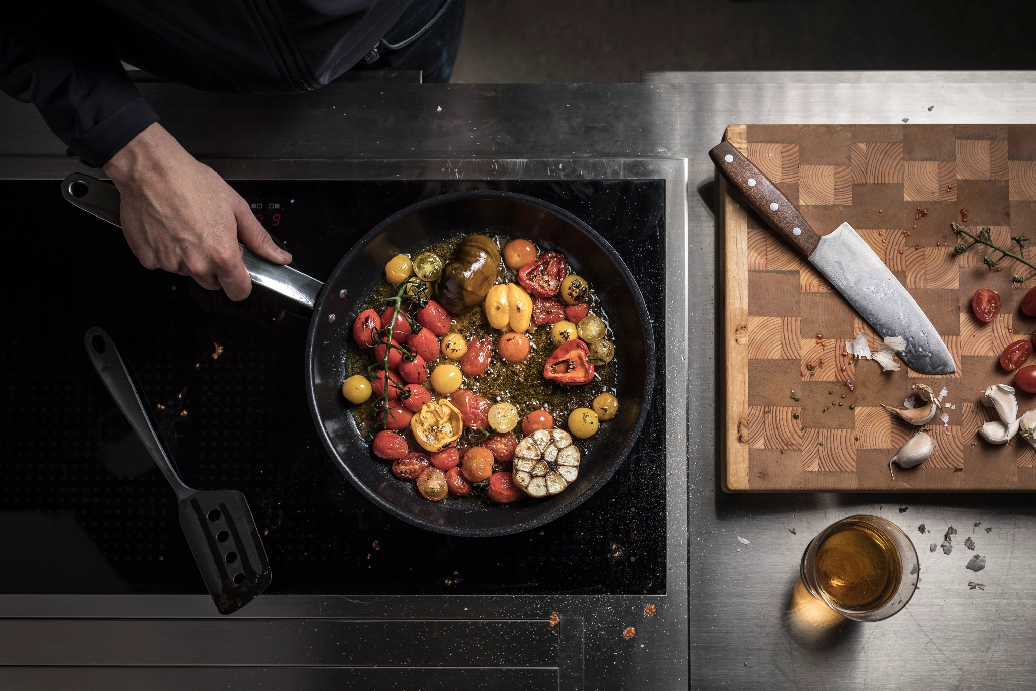 Fiskars paistinpannu liedellä täynnä tomatteja ja valkosipulia