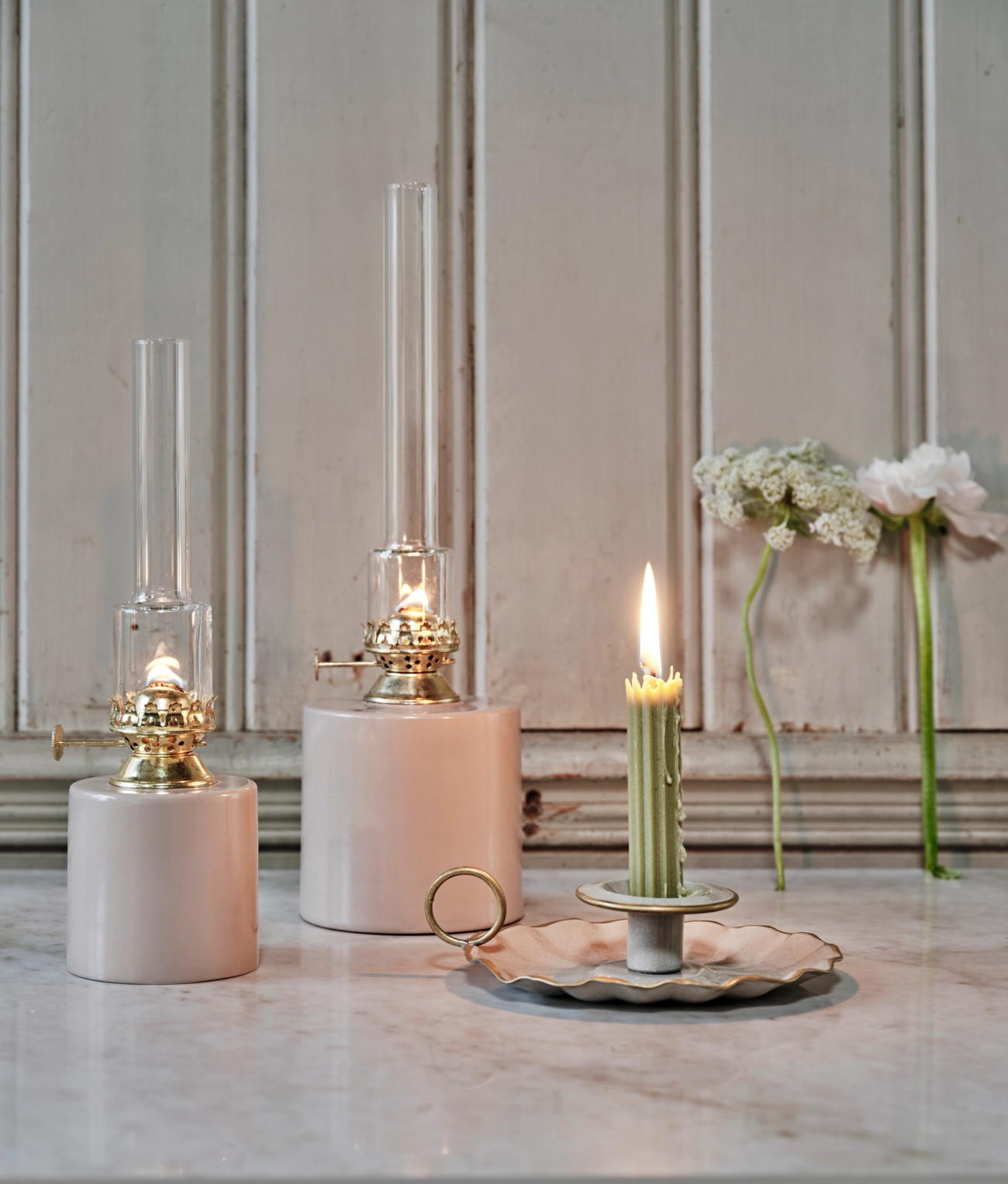 Oljelamper i beige med hvite blomster som skimtes i bakgrunnen