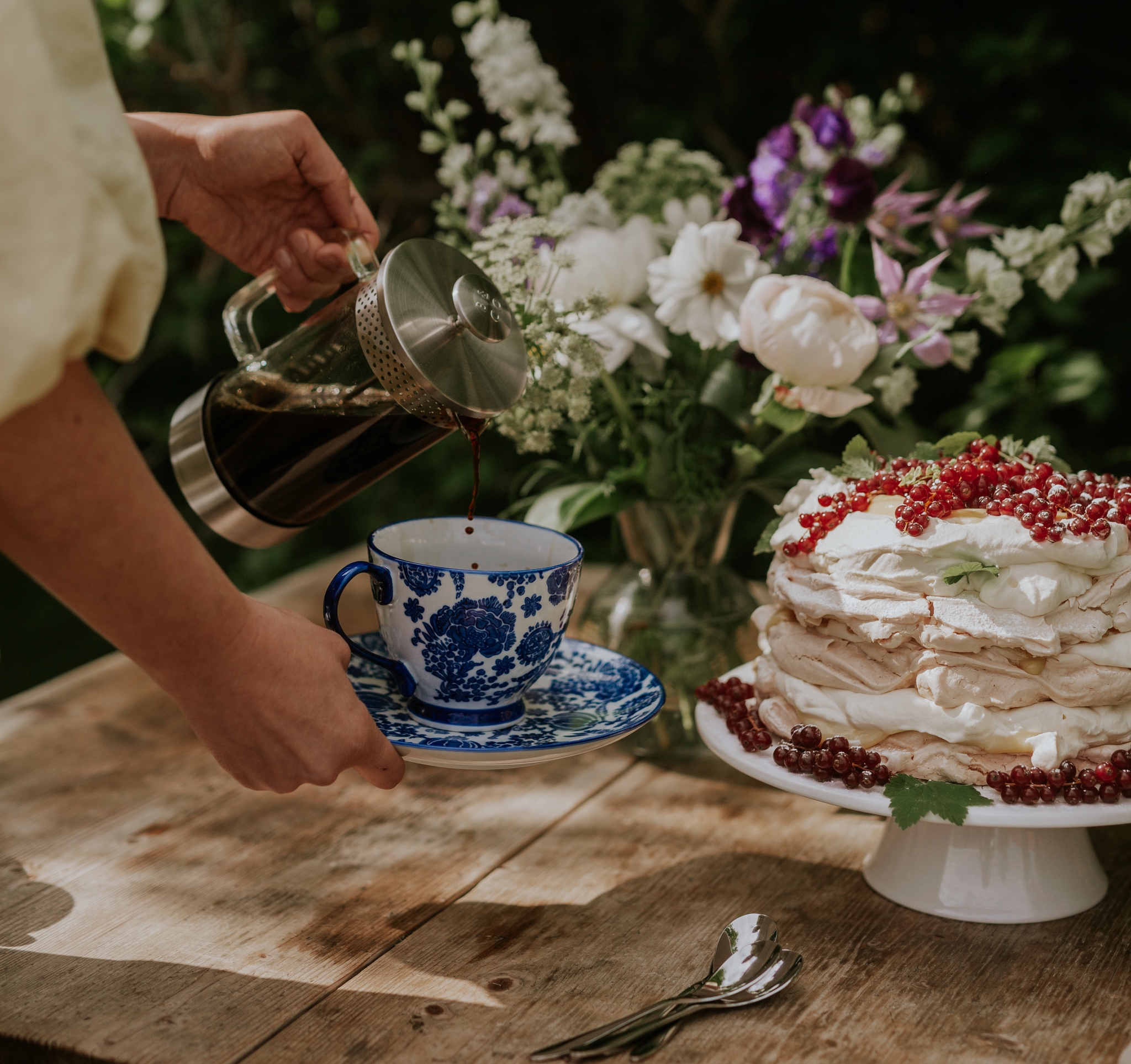 Pavlova kerman ja marjojen kera kakkuvadilla puupöydällä