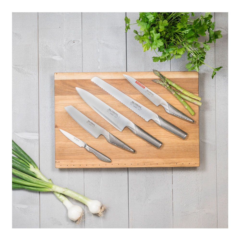 Fem knivar från Global som ligger på en skärbräda i trä