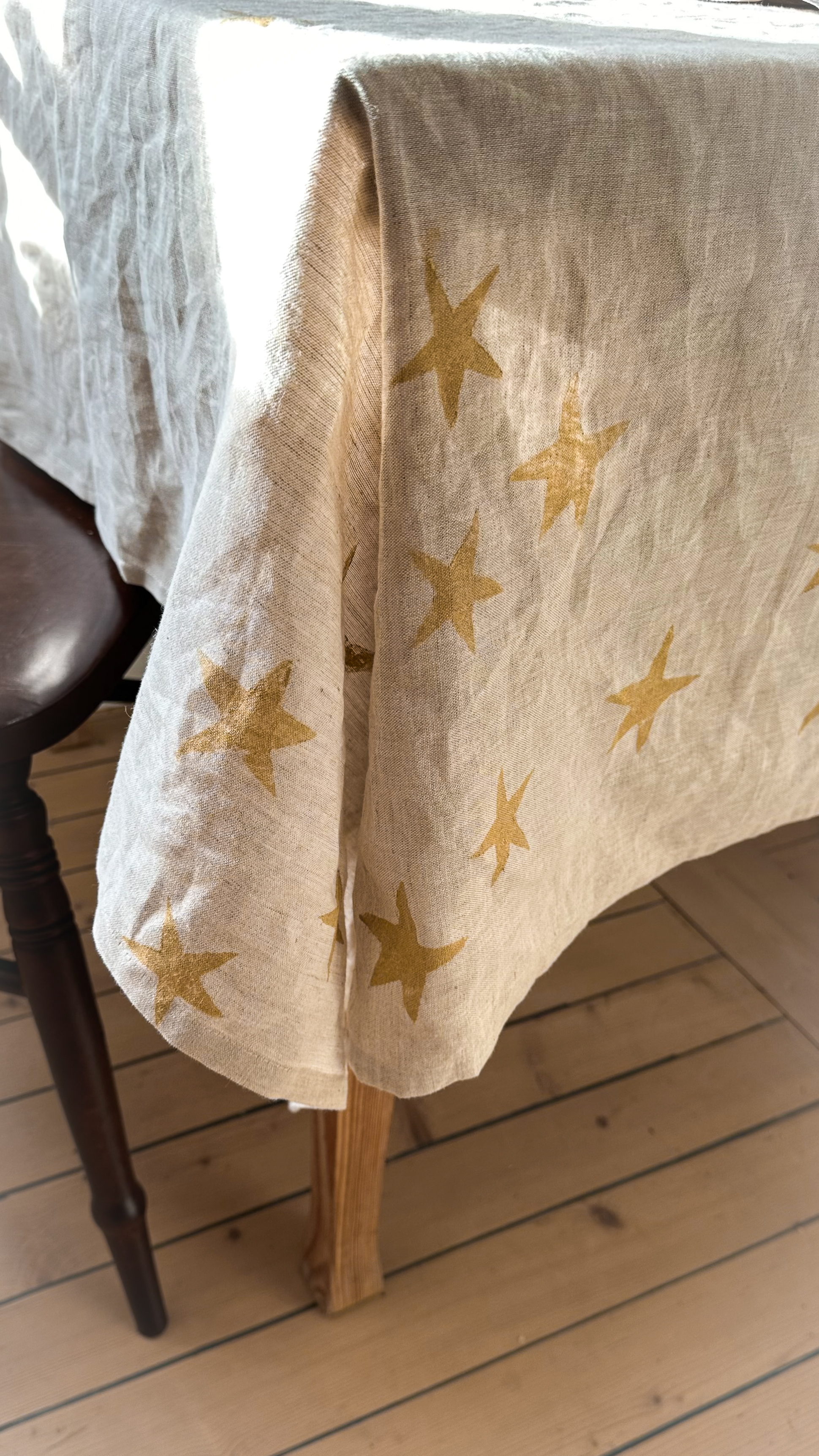 Beige linen tablecloth with gold stars draped over a table.